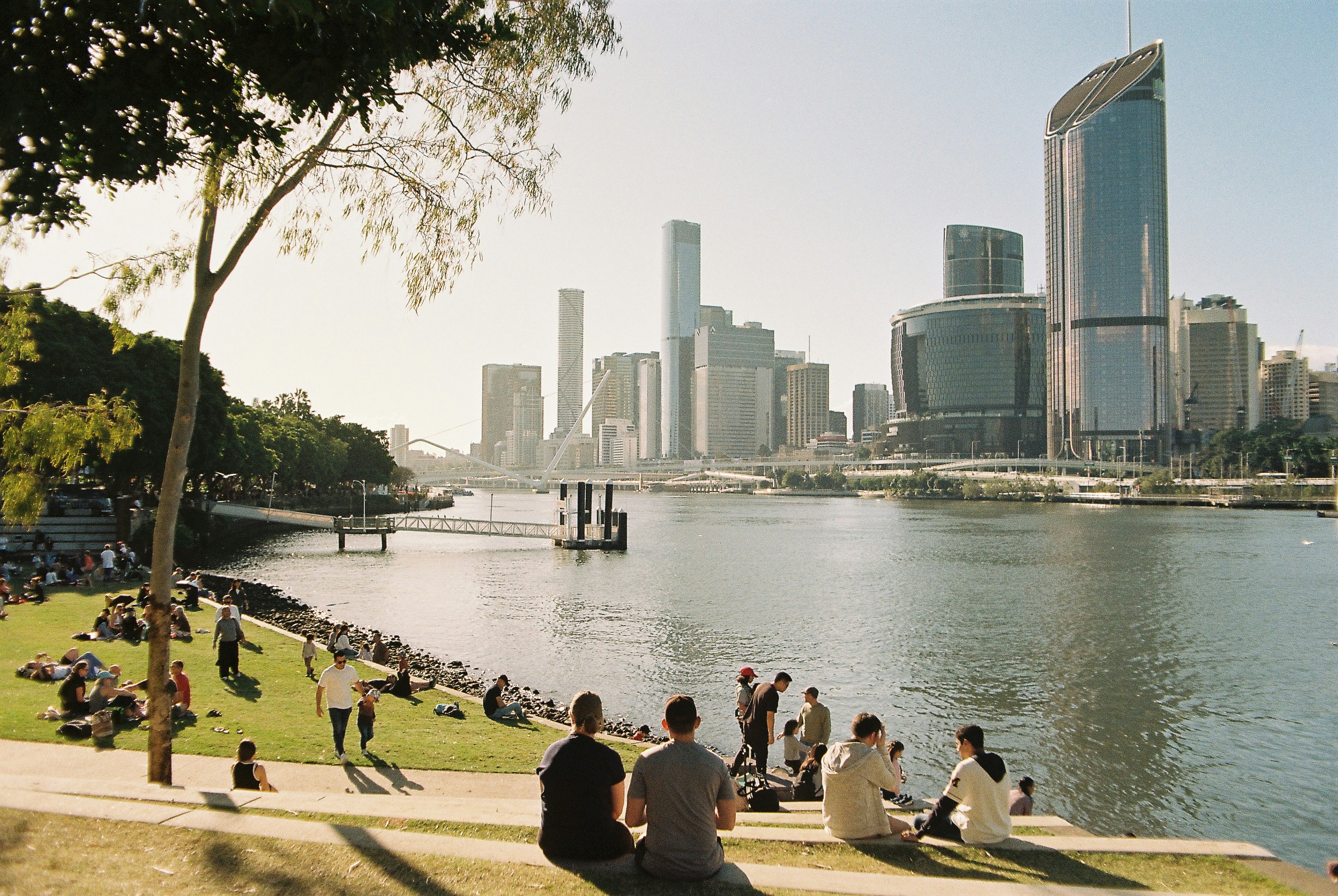 People relaxing by a river with city skyline background photo – Free ...