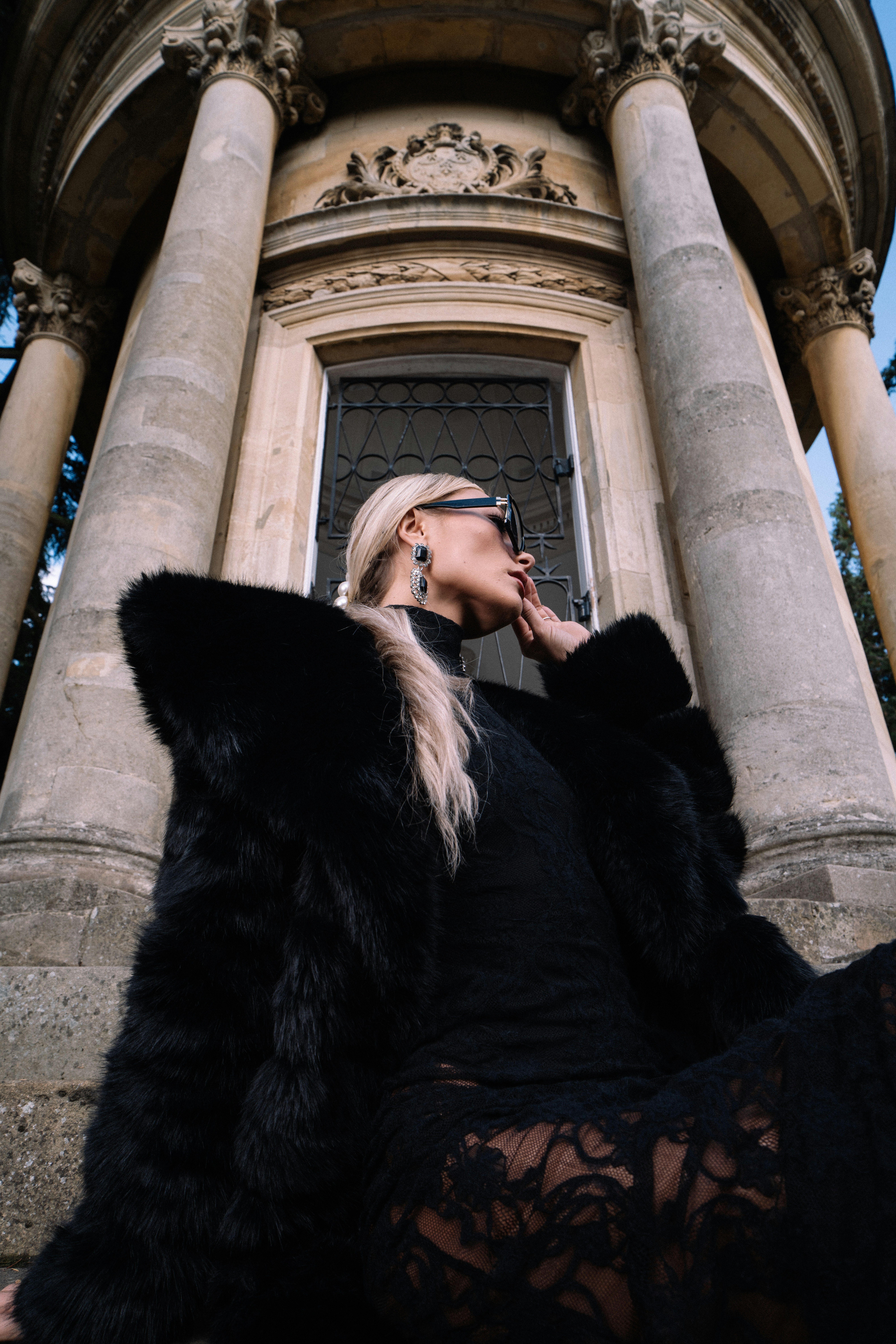 Woman in black fur coat near old building