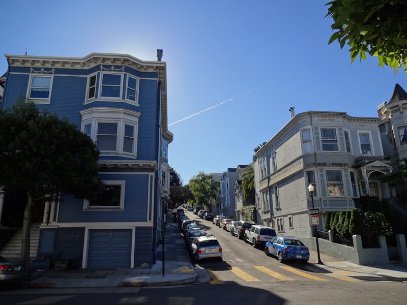 A row of historic Victorian homes along a tree-lined neighborhood street