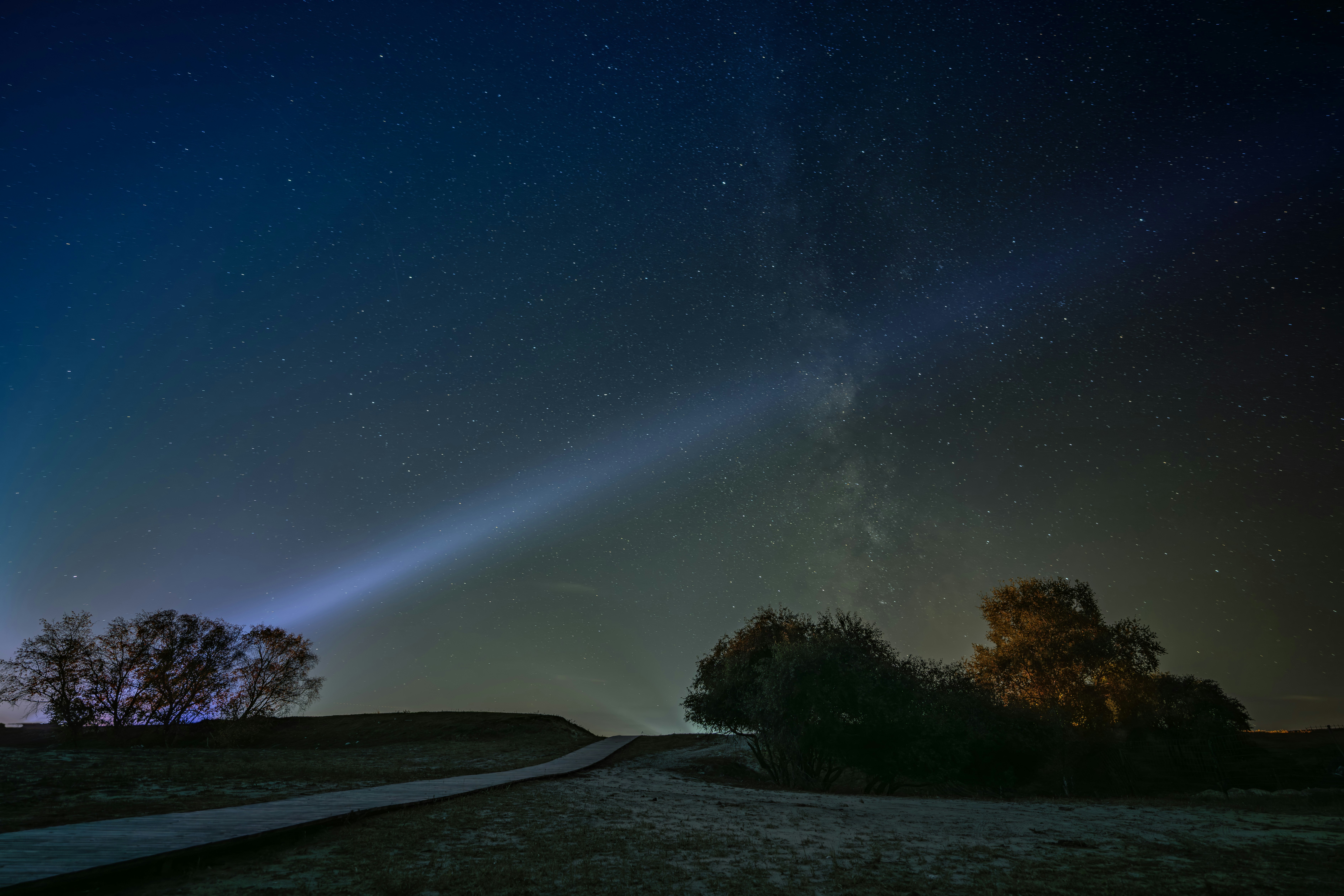 A beam of light shines through the starry night sky.