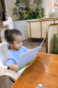 Young child sits in high chair reading a menu.