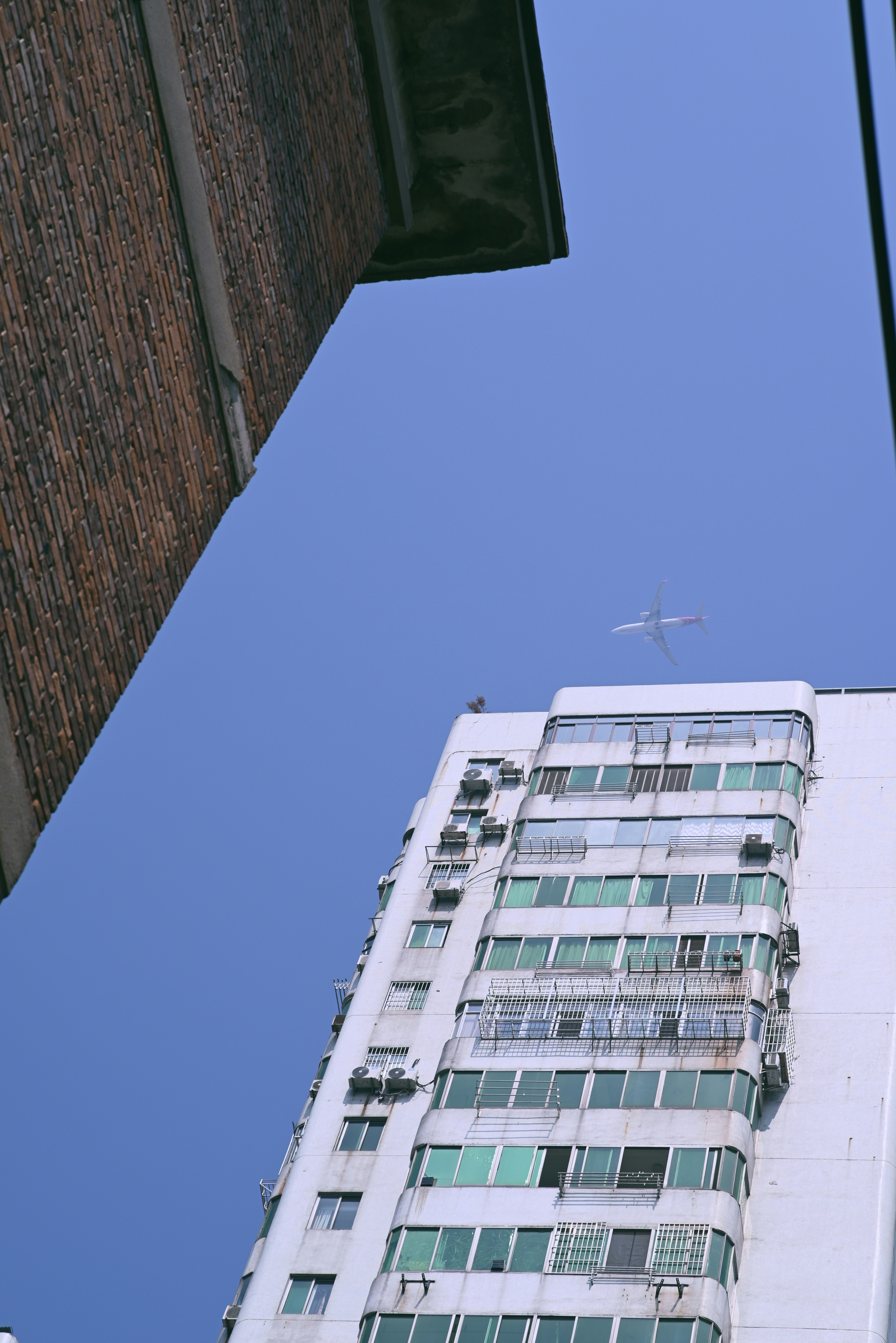 Looking up at buildings with a kite flying high.