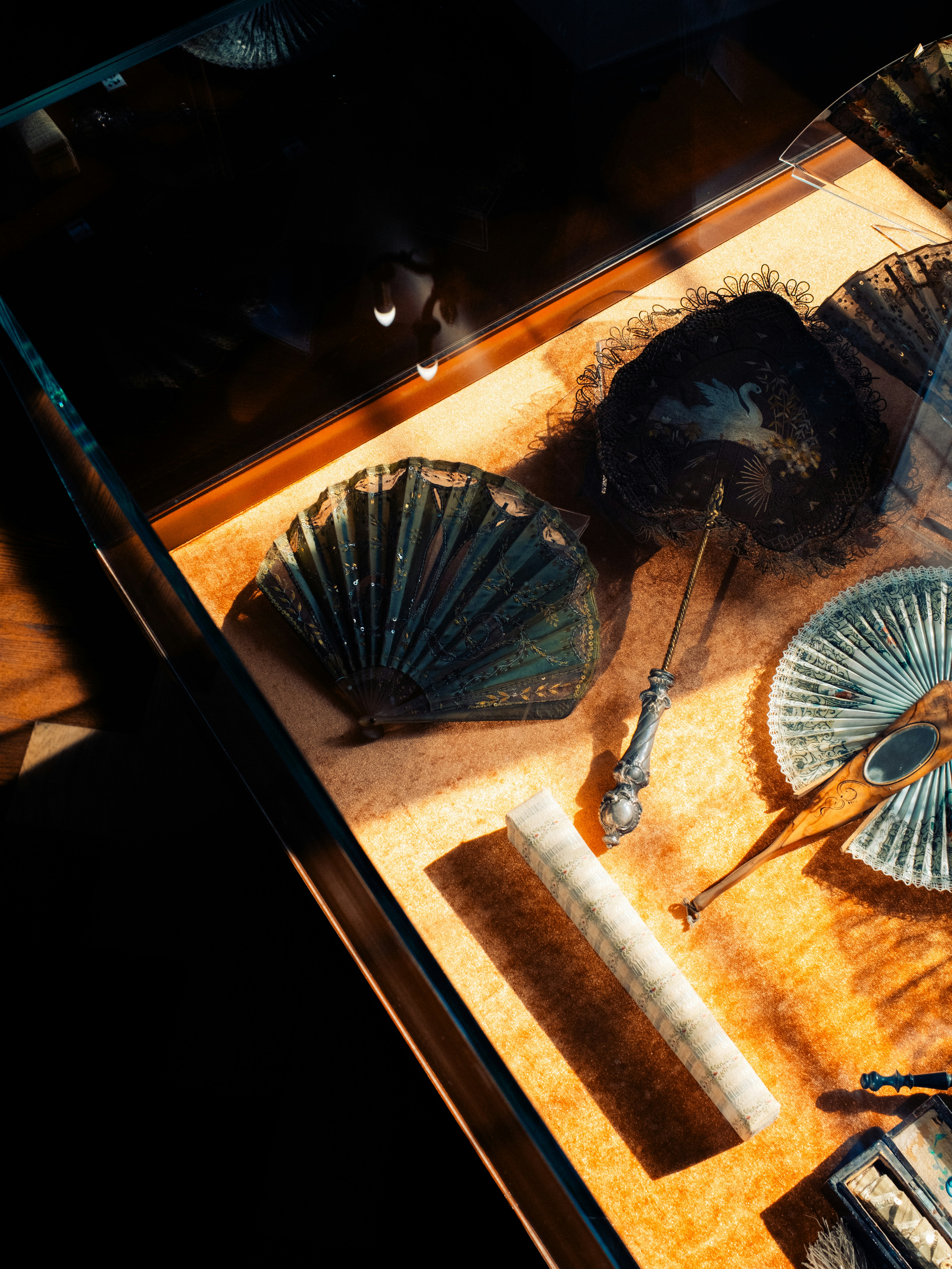 Colección de abanicos antiguos expuestos en una vitrina de museo.
