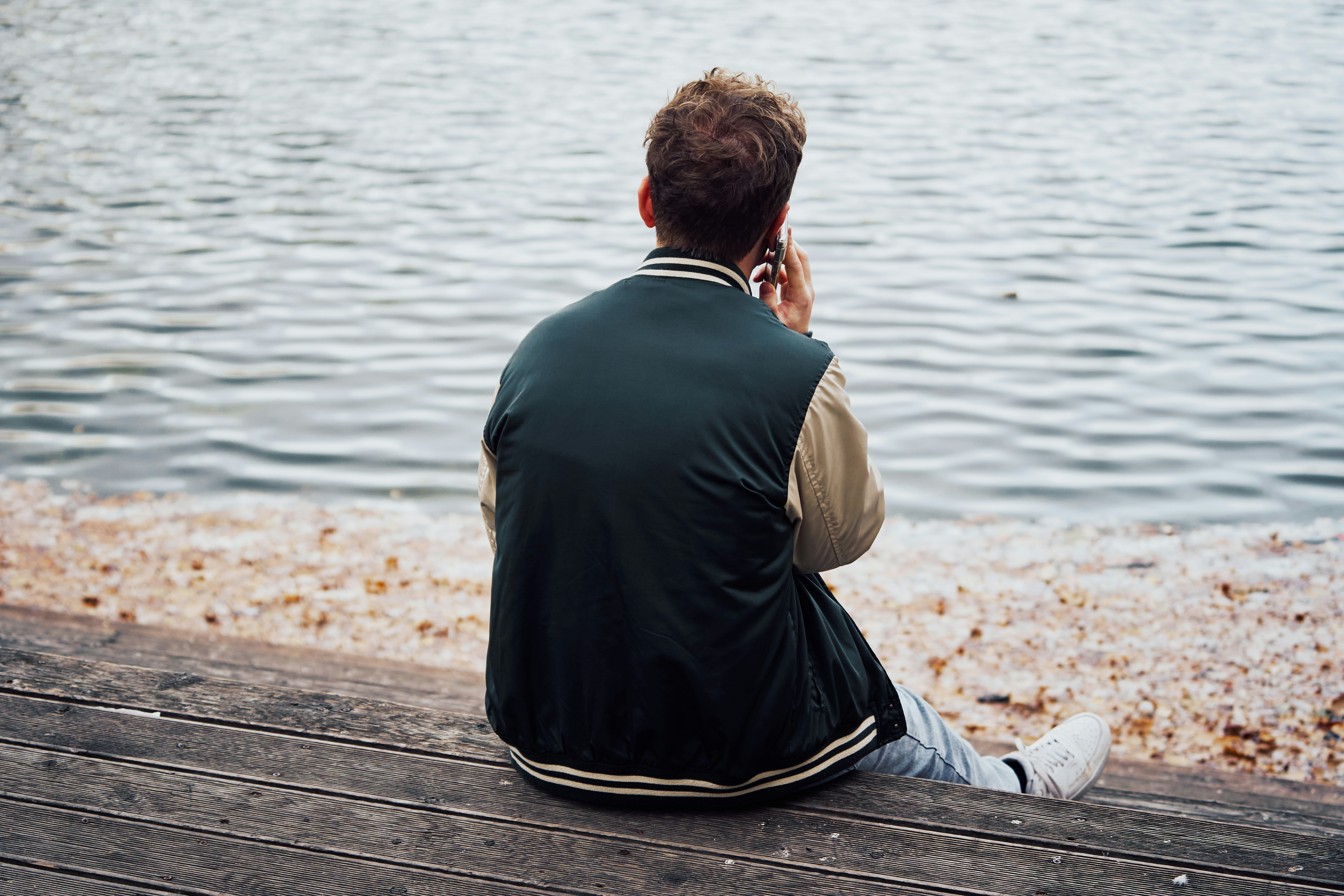 A distressed young woman sitting alone on a couch, staring at her smartphone screen with a sad and disappointed expression, illustrating the emotional impact of being ghosted.