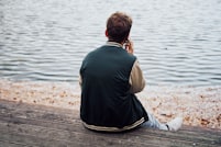 Personne assise pres de l'eau utilisant son smartphone