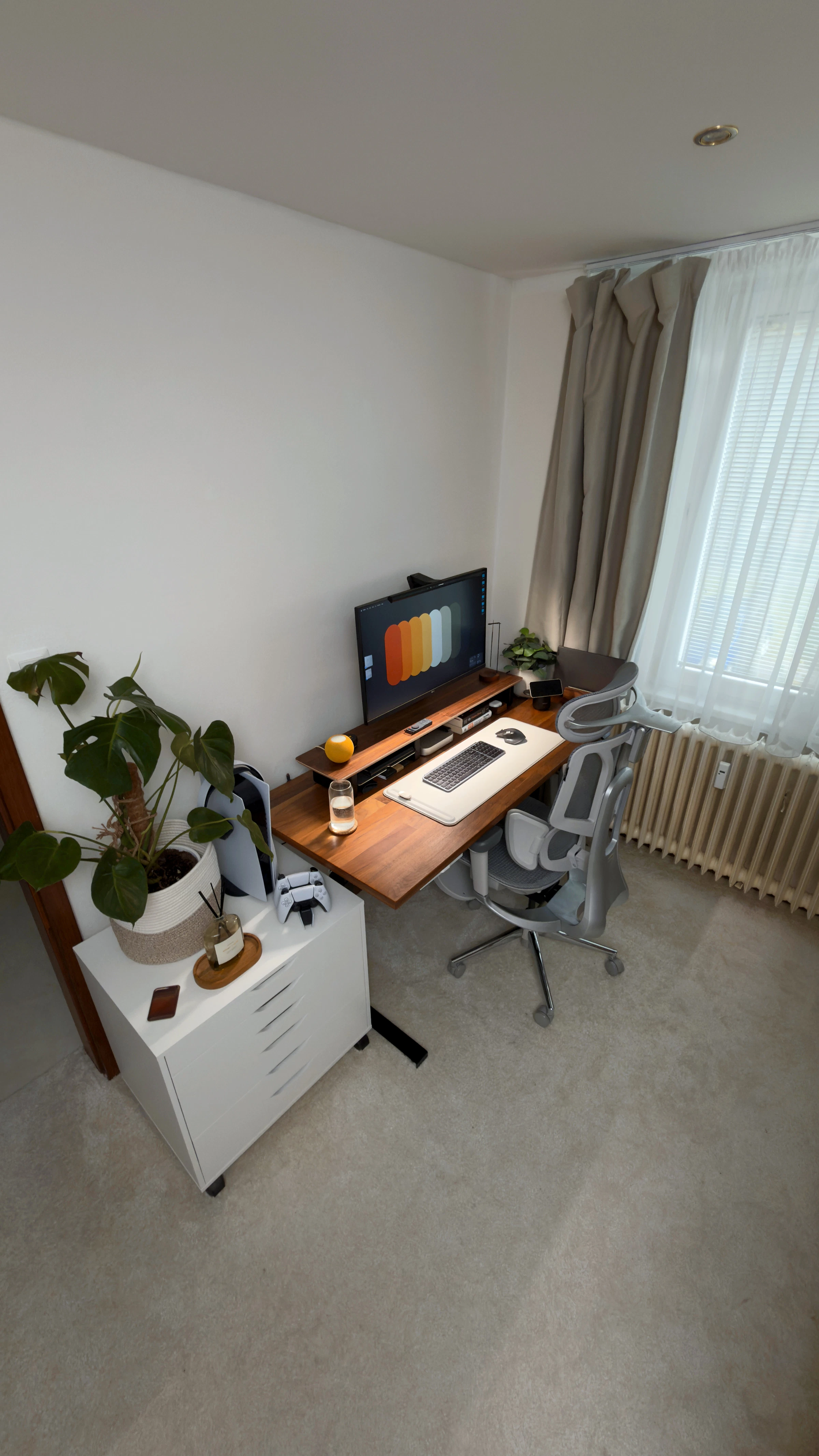 Modern home office with an adjustable standing desk, monitor, keyboard and office chair
