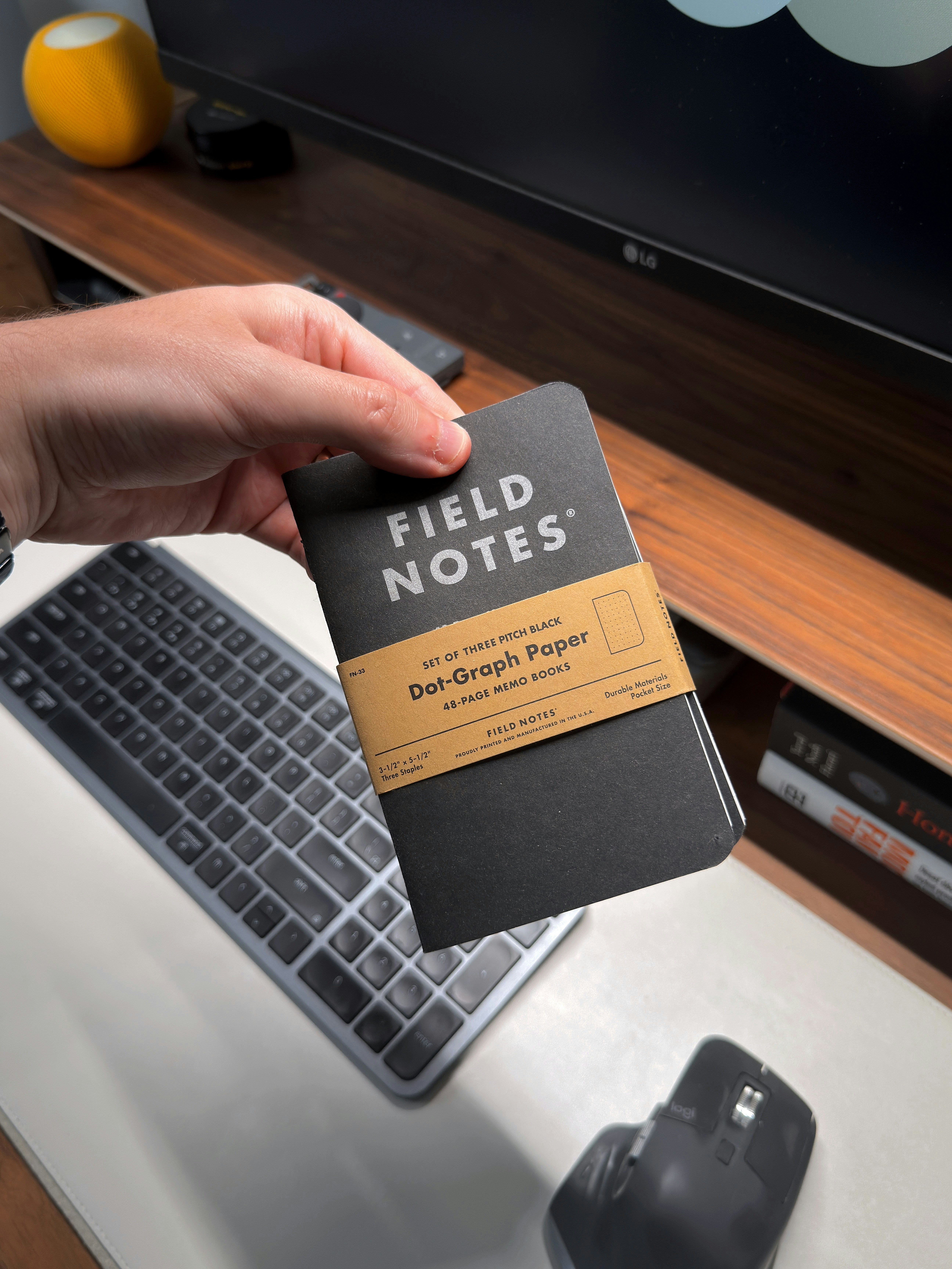 Hand holding a small black field notes notebook.