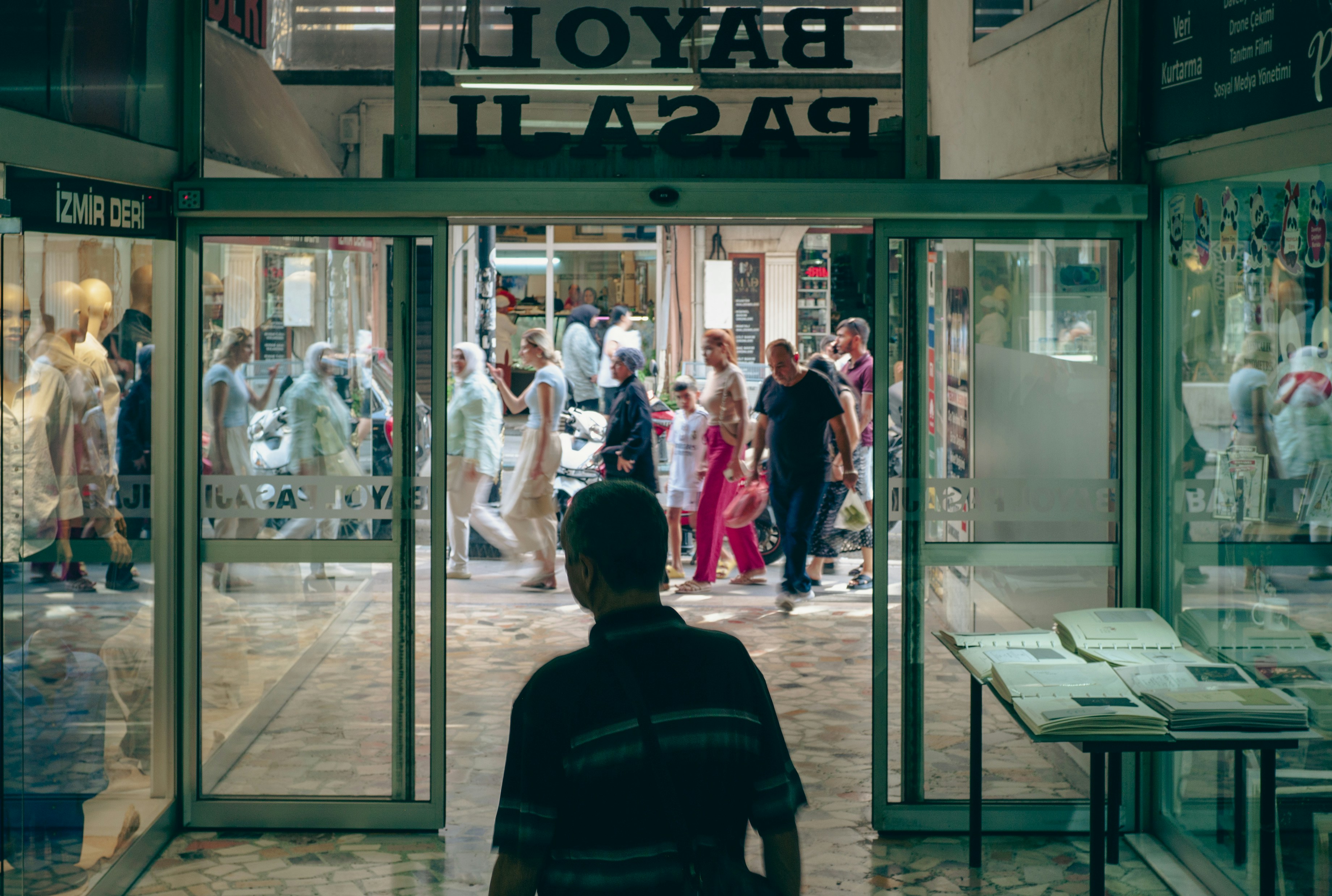 People walking through automatic glass doors into a plaza.