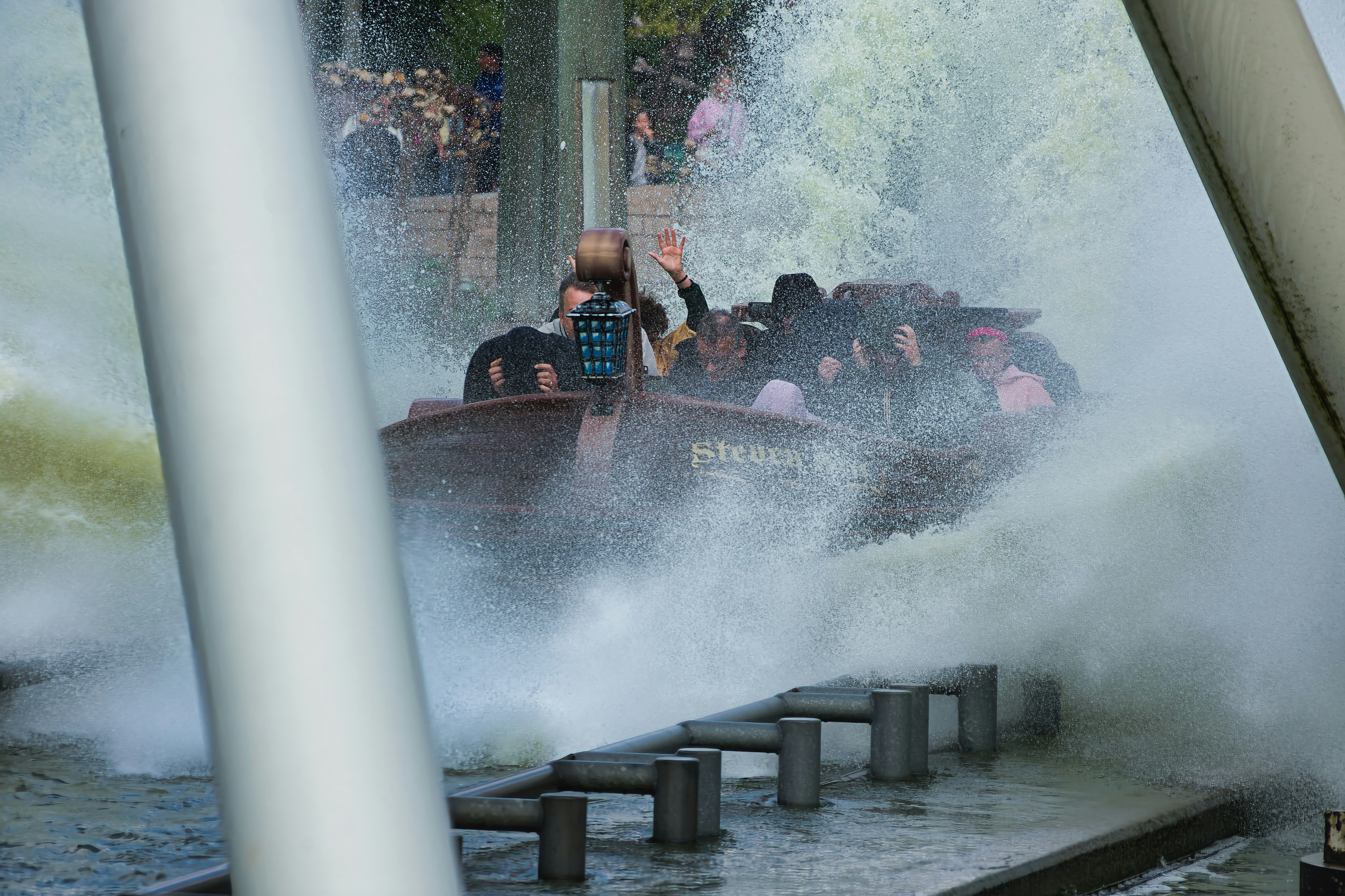 People on a log flume ride splash through water.