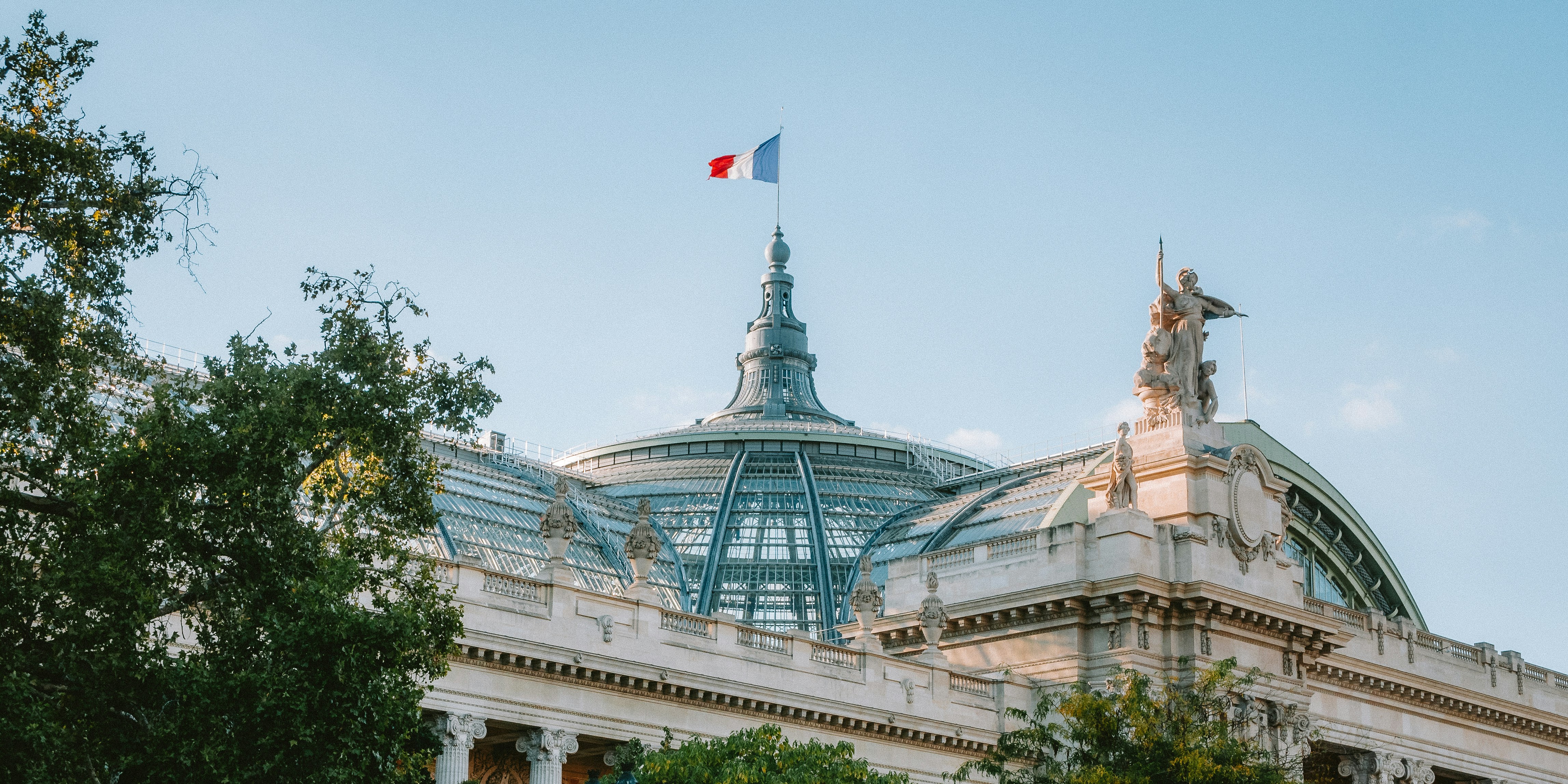 Bâtiment du Grand Palais avec drapeau français sous ciel bleu