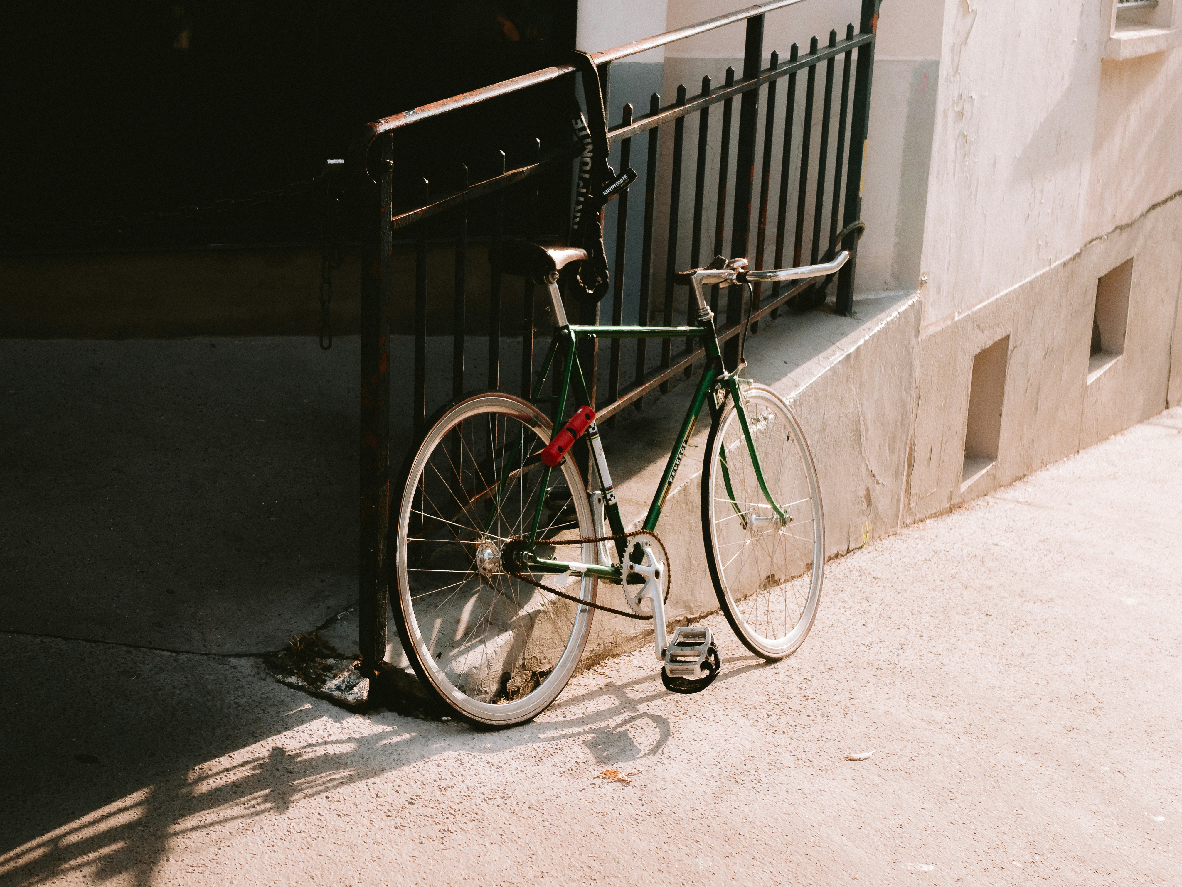 A bicycle leans against a wall in sunlight.