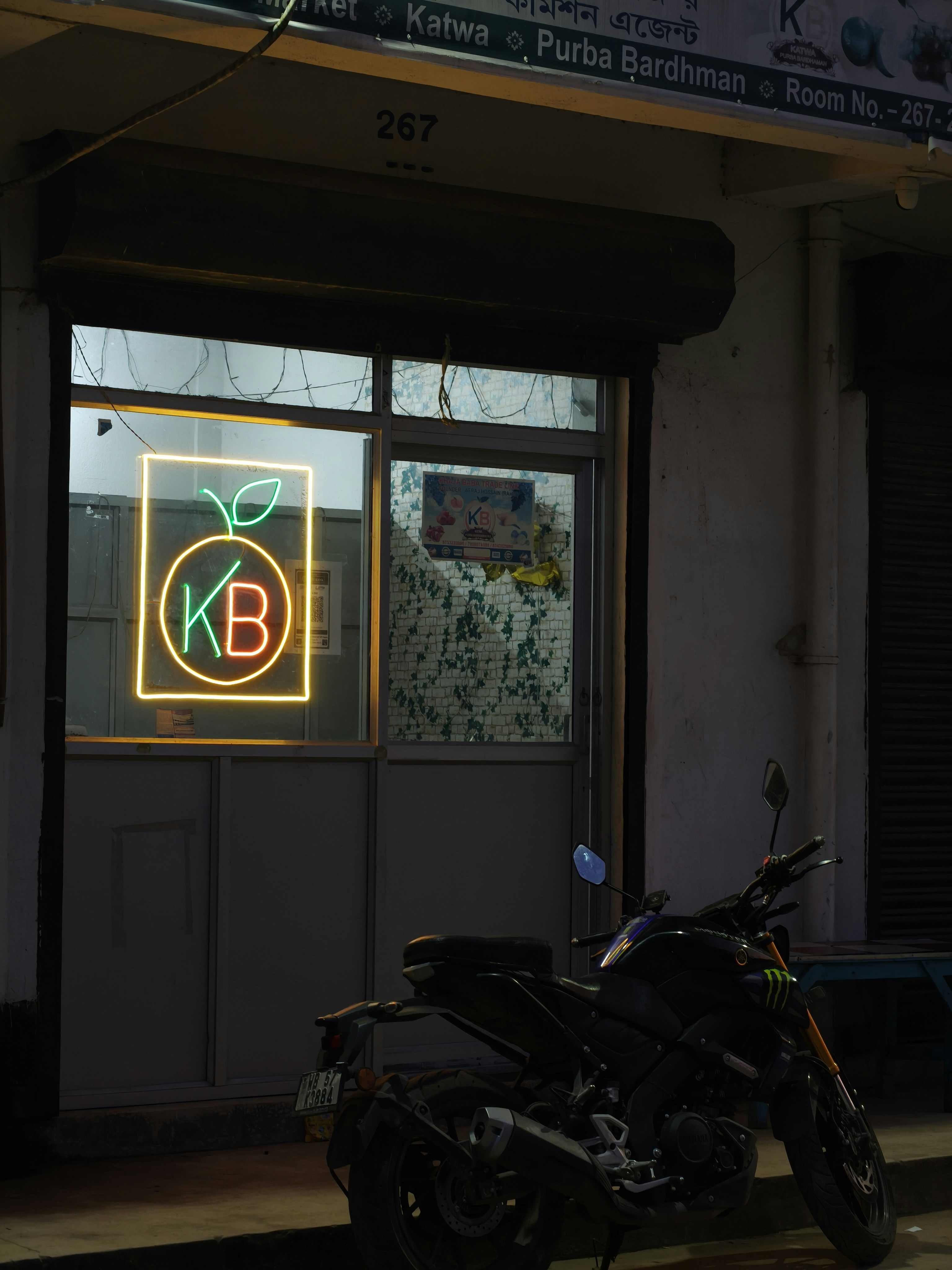 Tanda neon dengan kb dan oranye di luar toko di malam hari