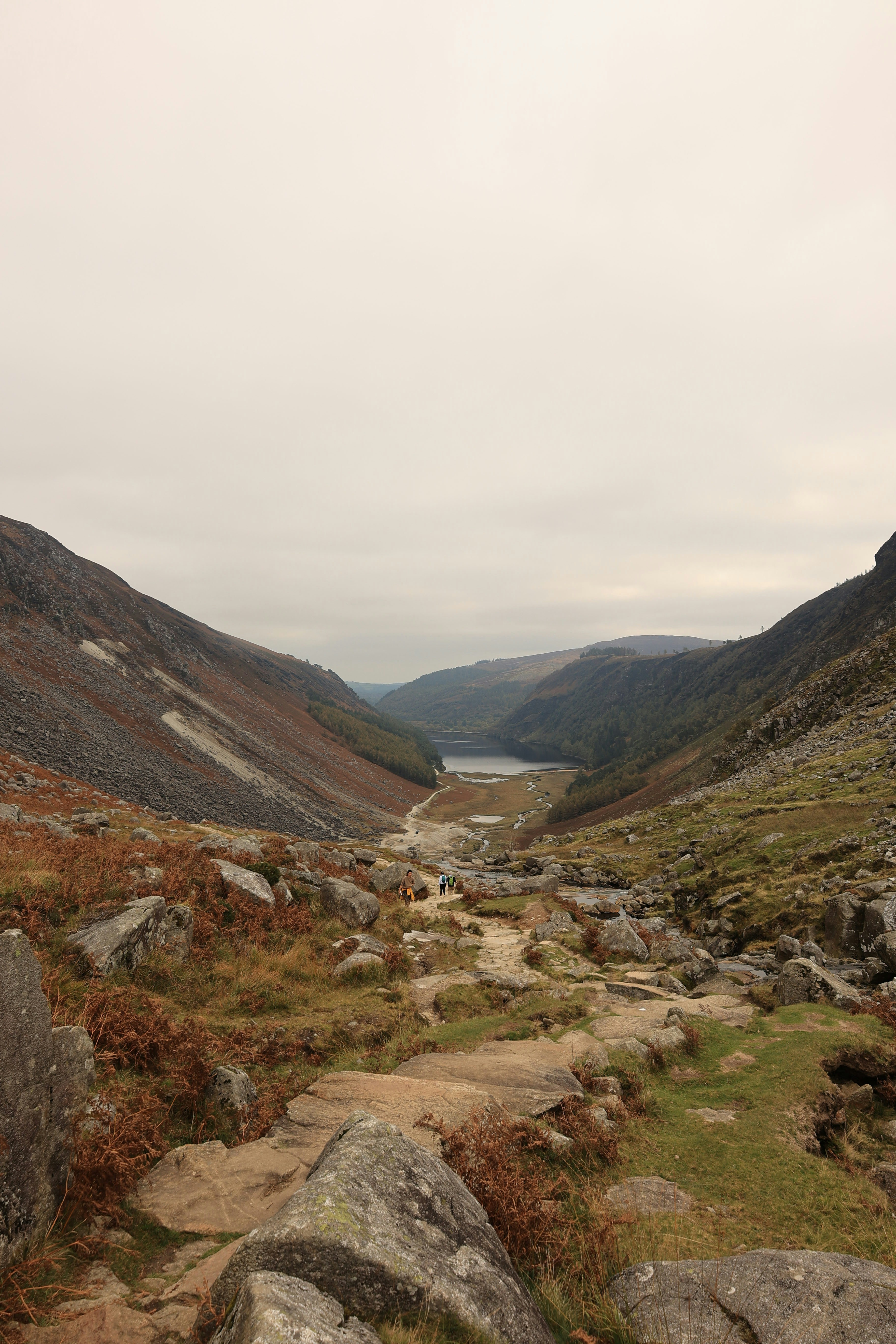 Rocky path leading to a distant lake in a valley