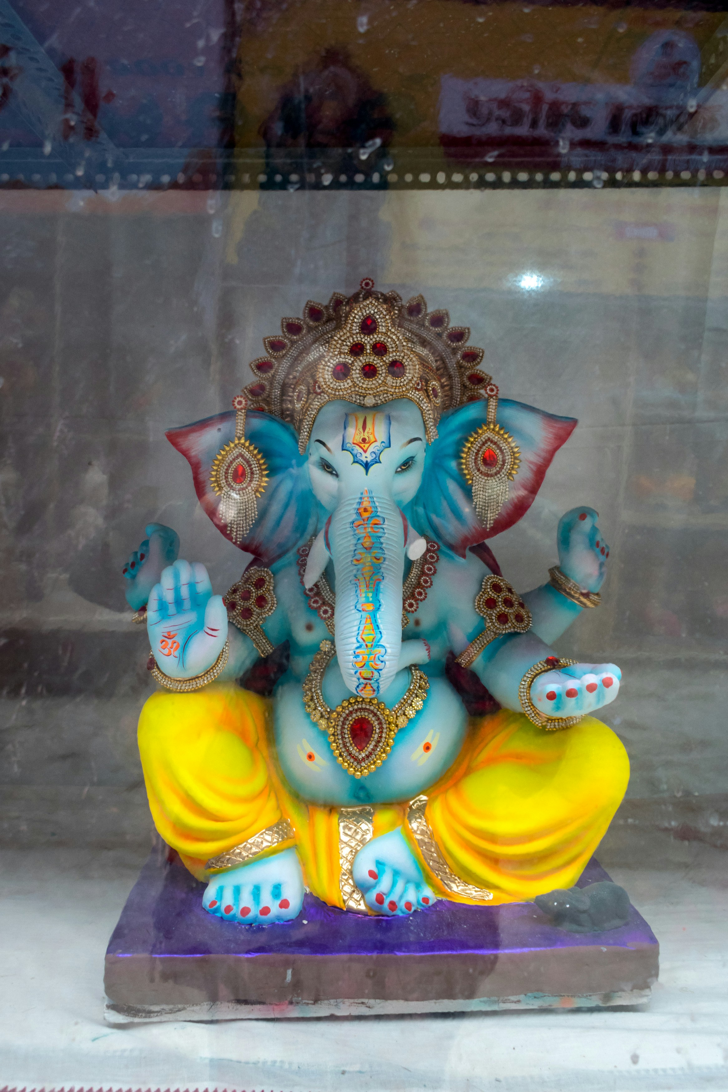A blue statue of ganesha sits cross-legged.