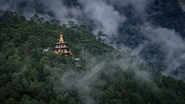 Temple nestled in a misty, forested mountainside.