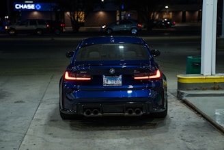 A dark blue BMW parked at night