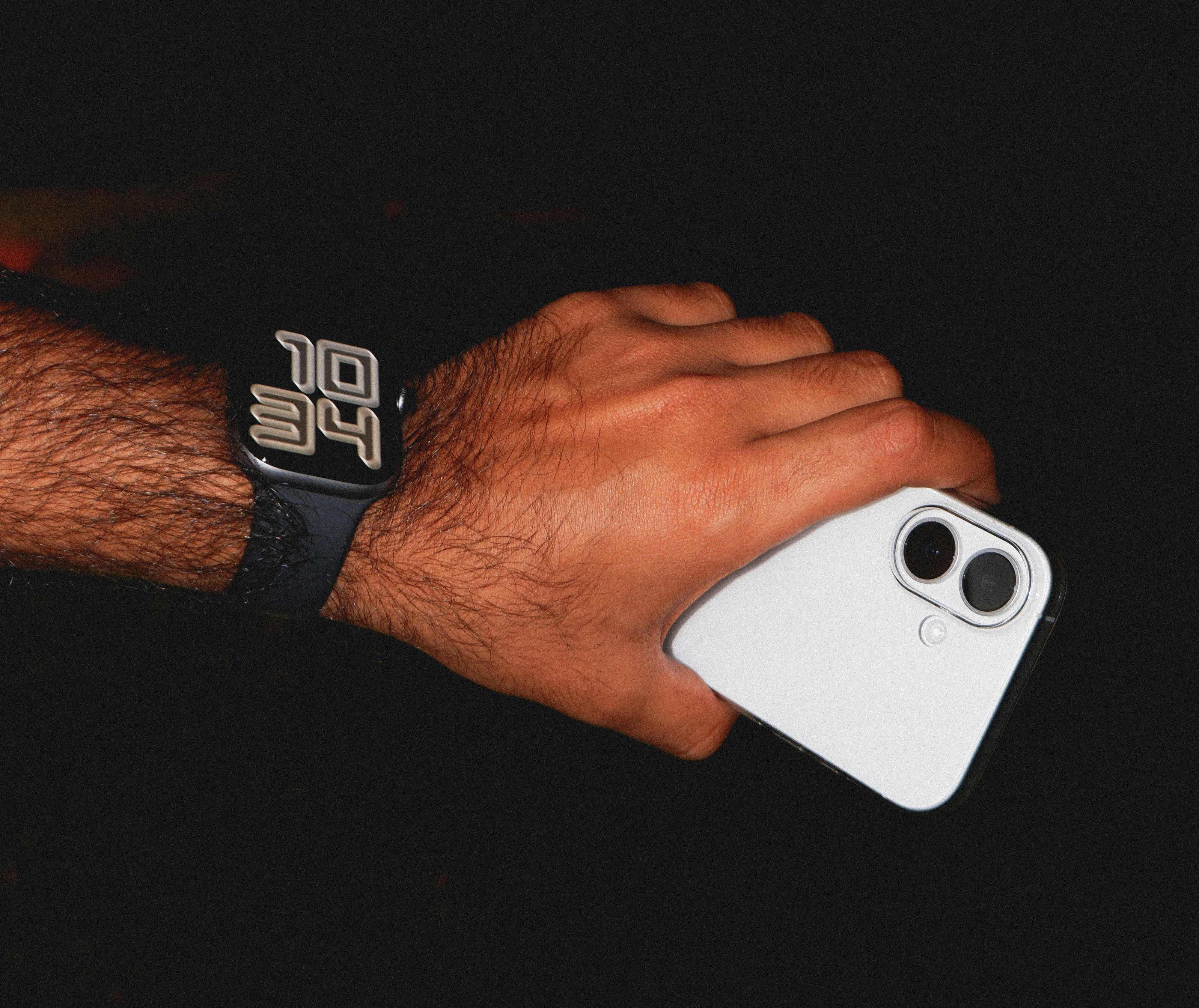 Man's hand holding a white smartphone and wearing a smartwatch