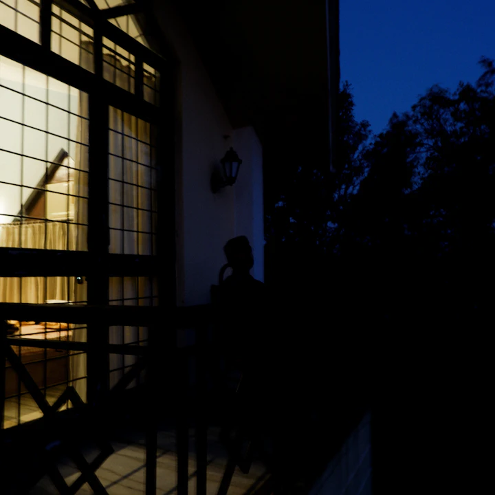 Window lit from inside at dusk with dark trees outside