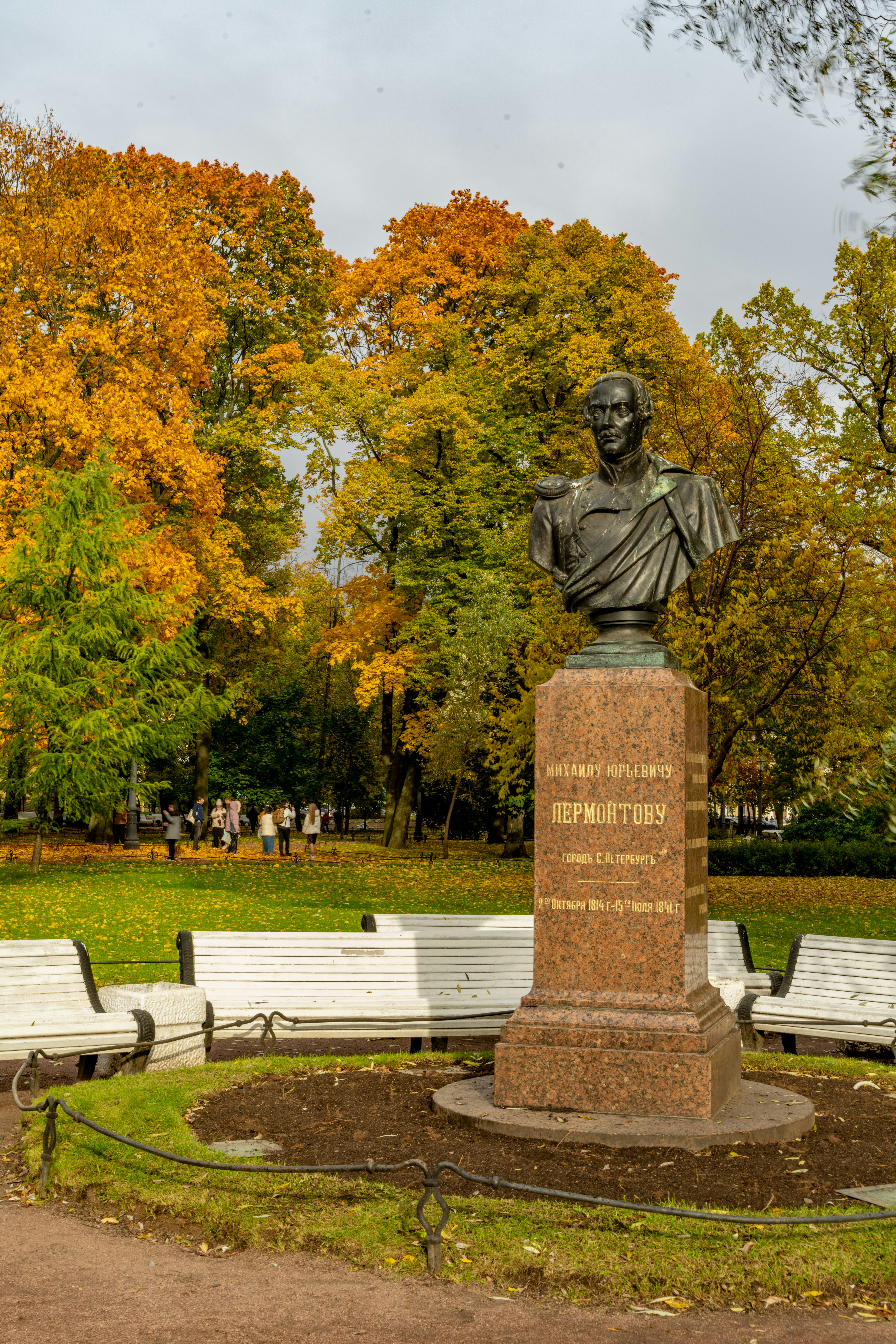 Bust monument in park with autumn trees and benches