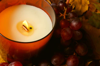 Lit candle with grapes and autumn leaves