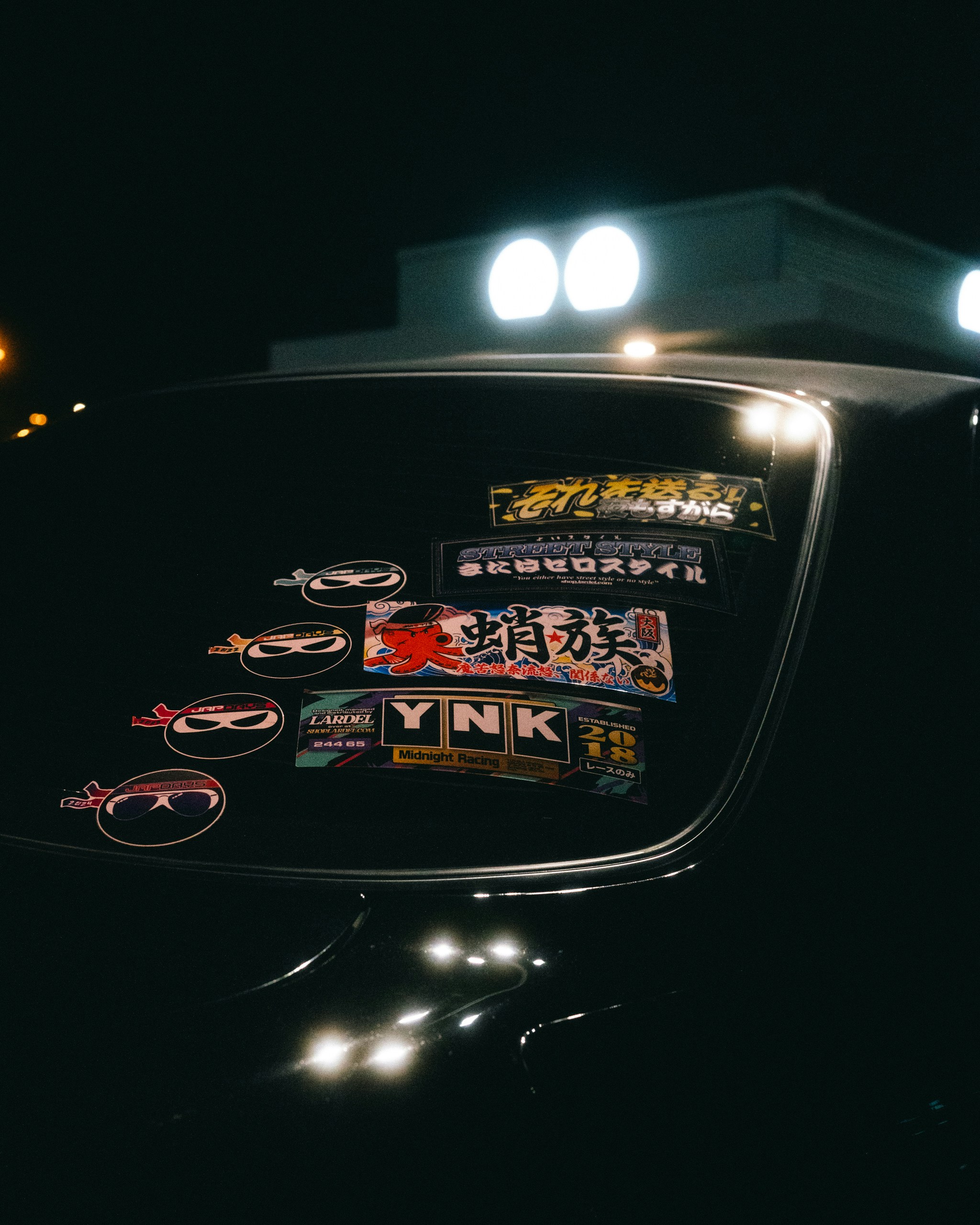 Car window covered in various stickers at night