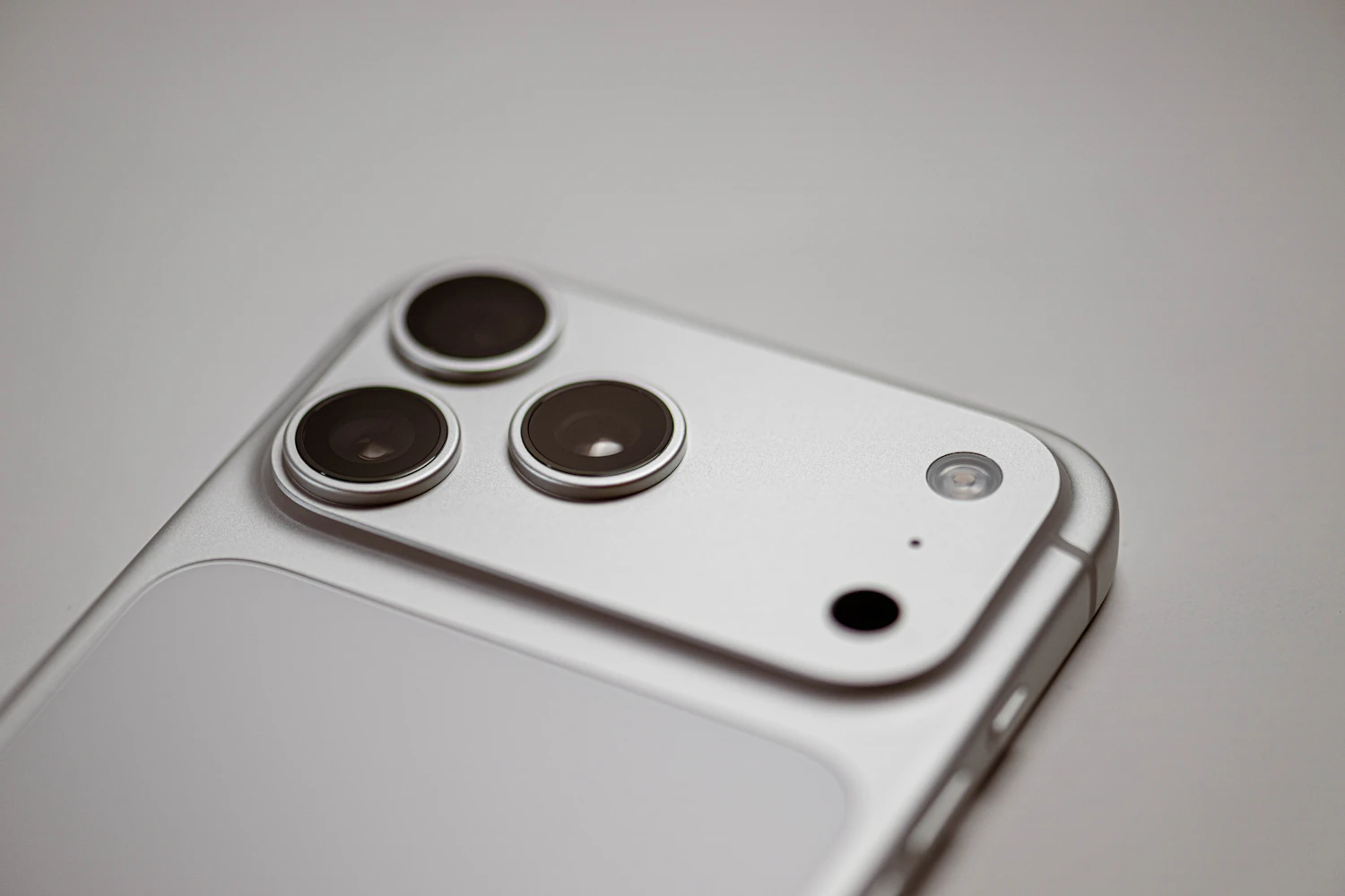 Close on the three camera lenses of a white phone, where the Lens Ring Set sits