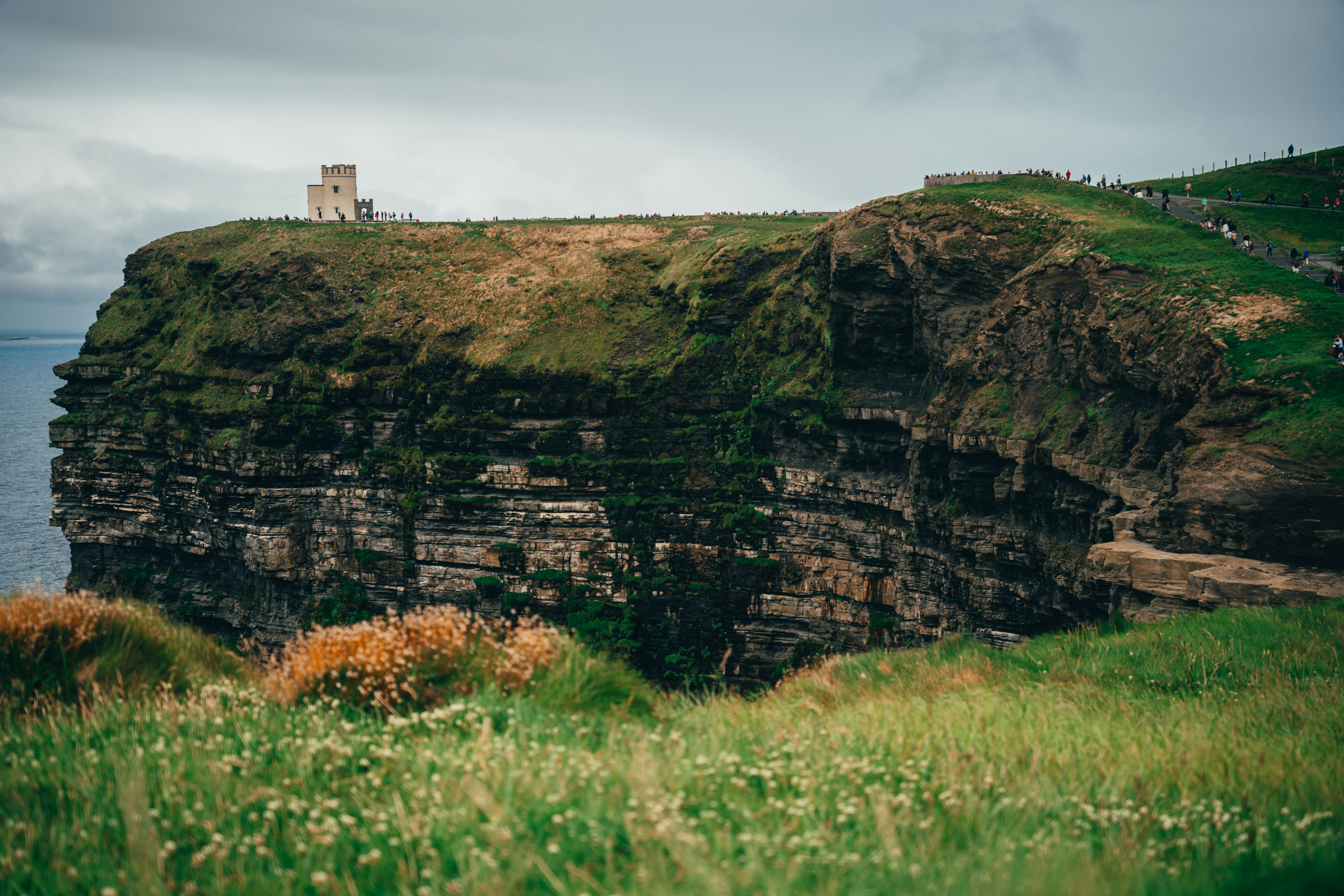 Torre de piedra en un acantilado cubierto de hierba con vistas al océano