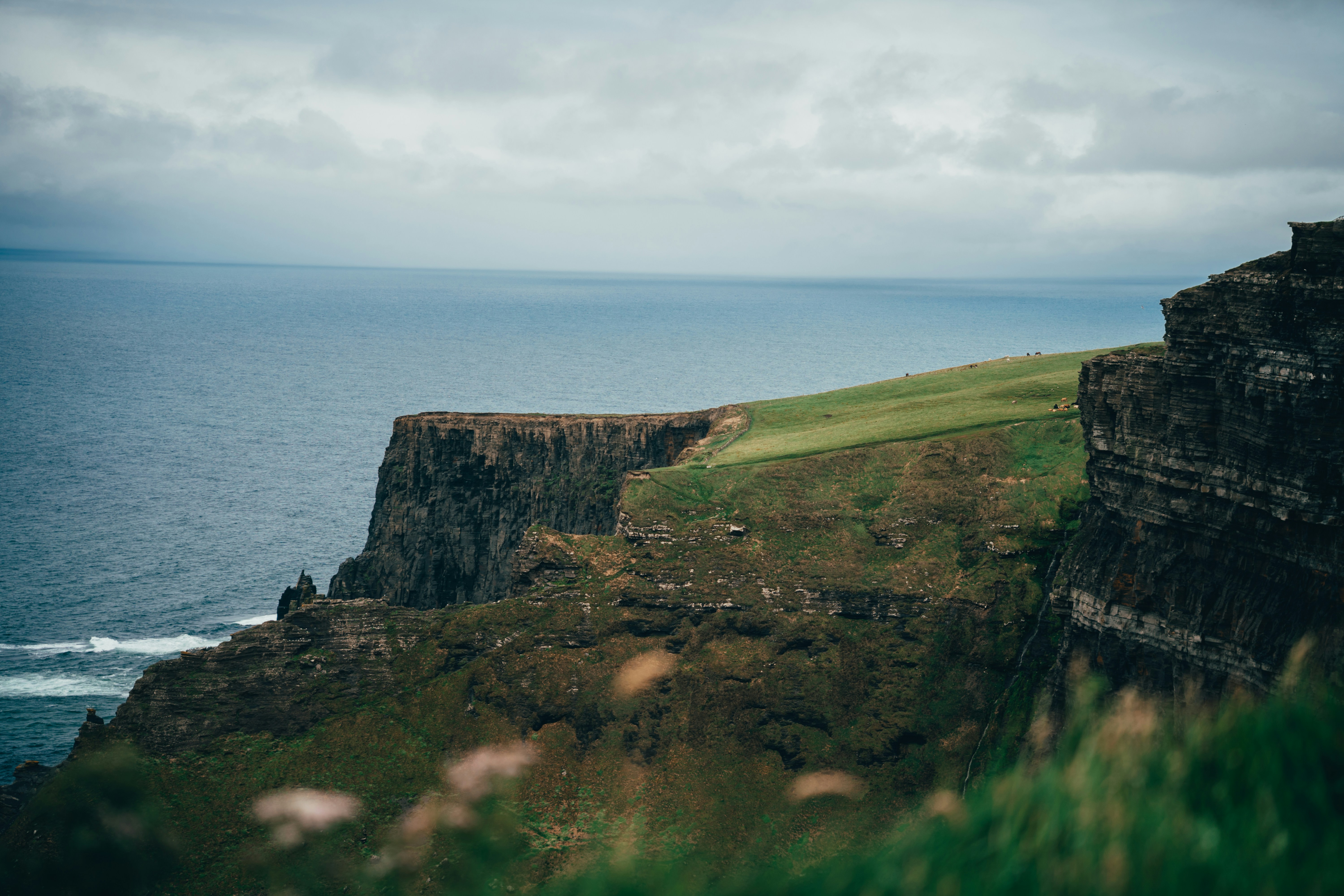Acantilados escarpados se encuentran con el océano bajo un cielo nublado