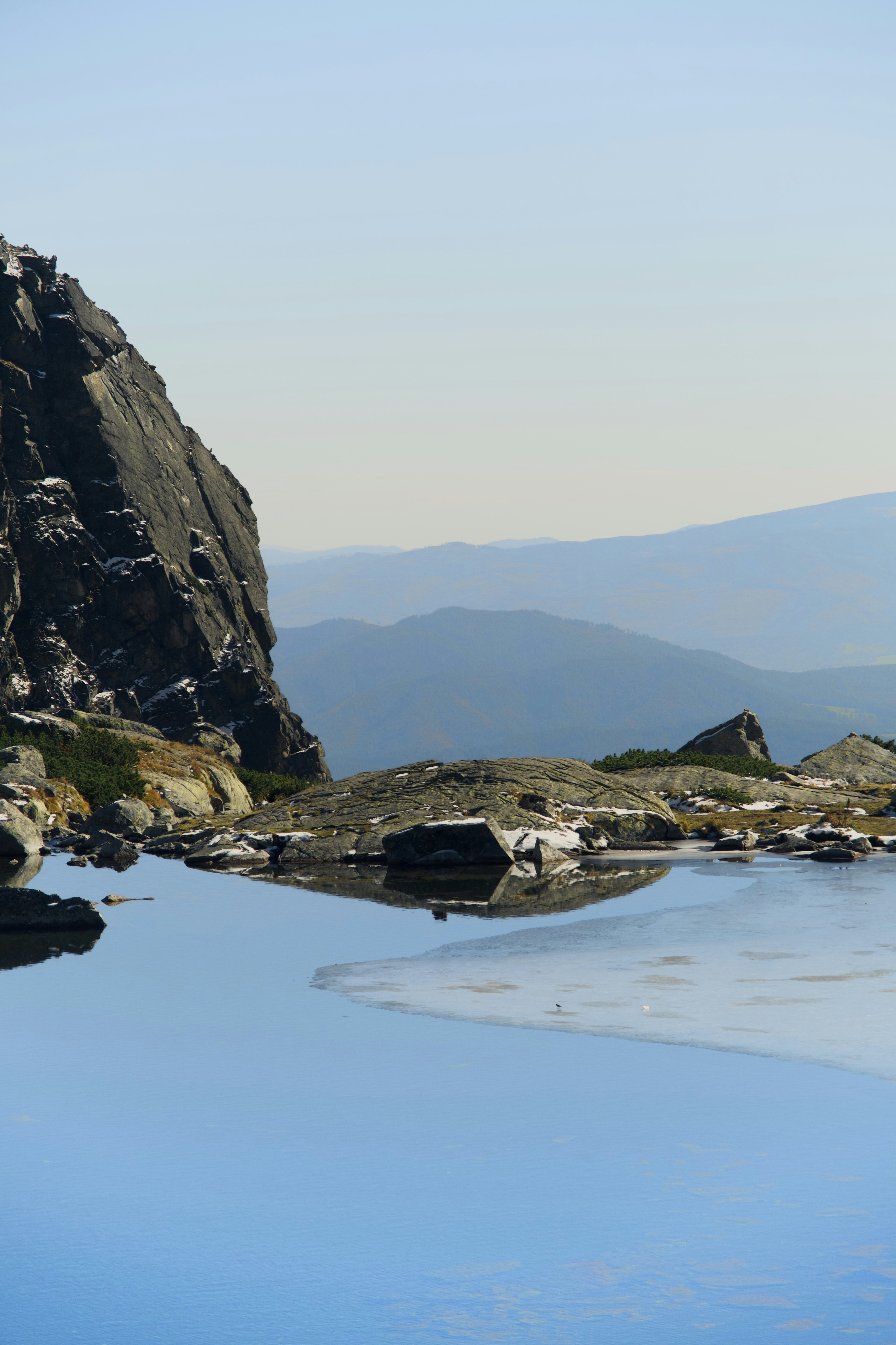 Lac de montagne rocheux avec des collines bleues lointaines