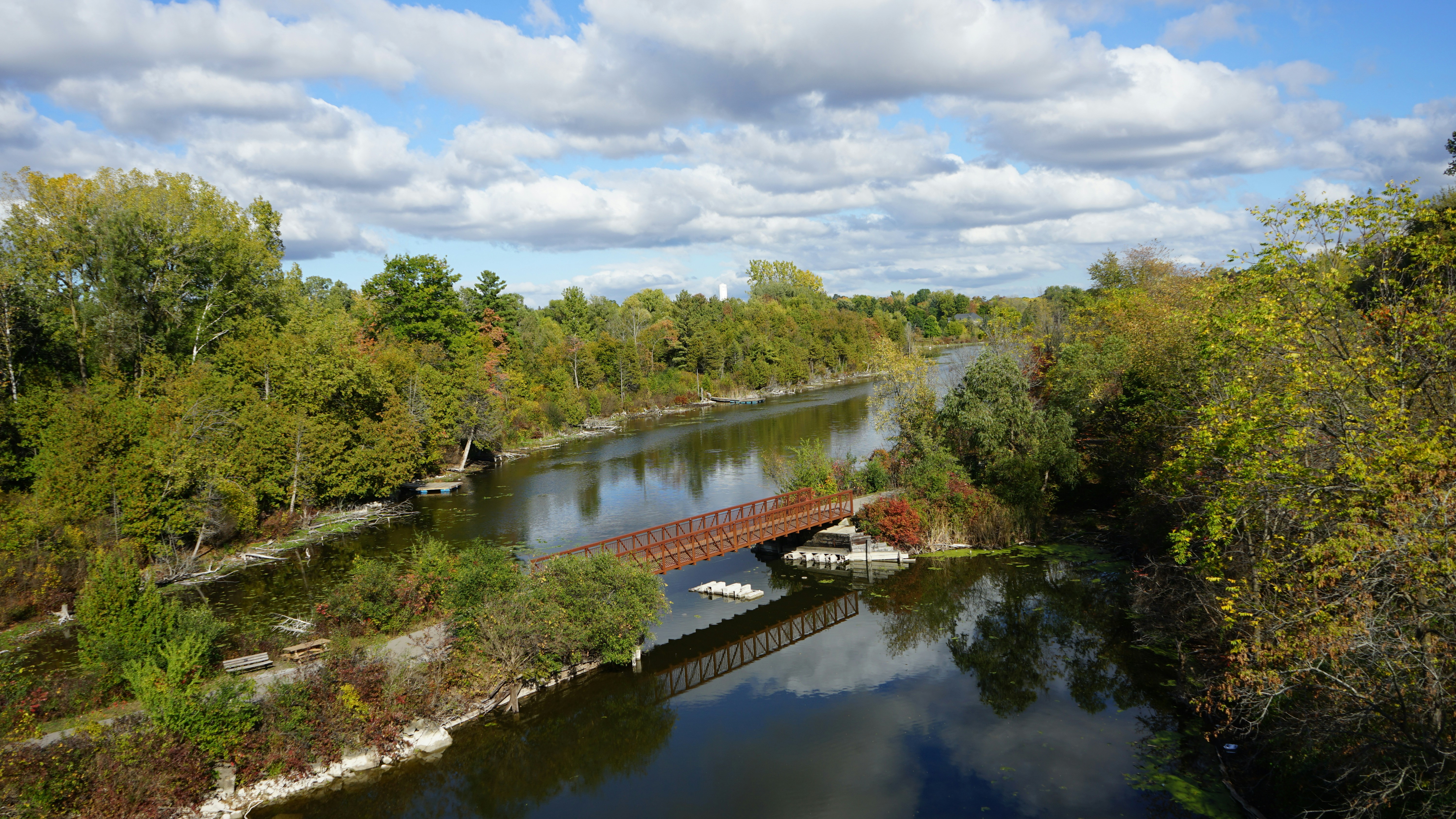 A tranquil canal with a small bridge surrounded by trees.