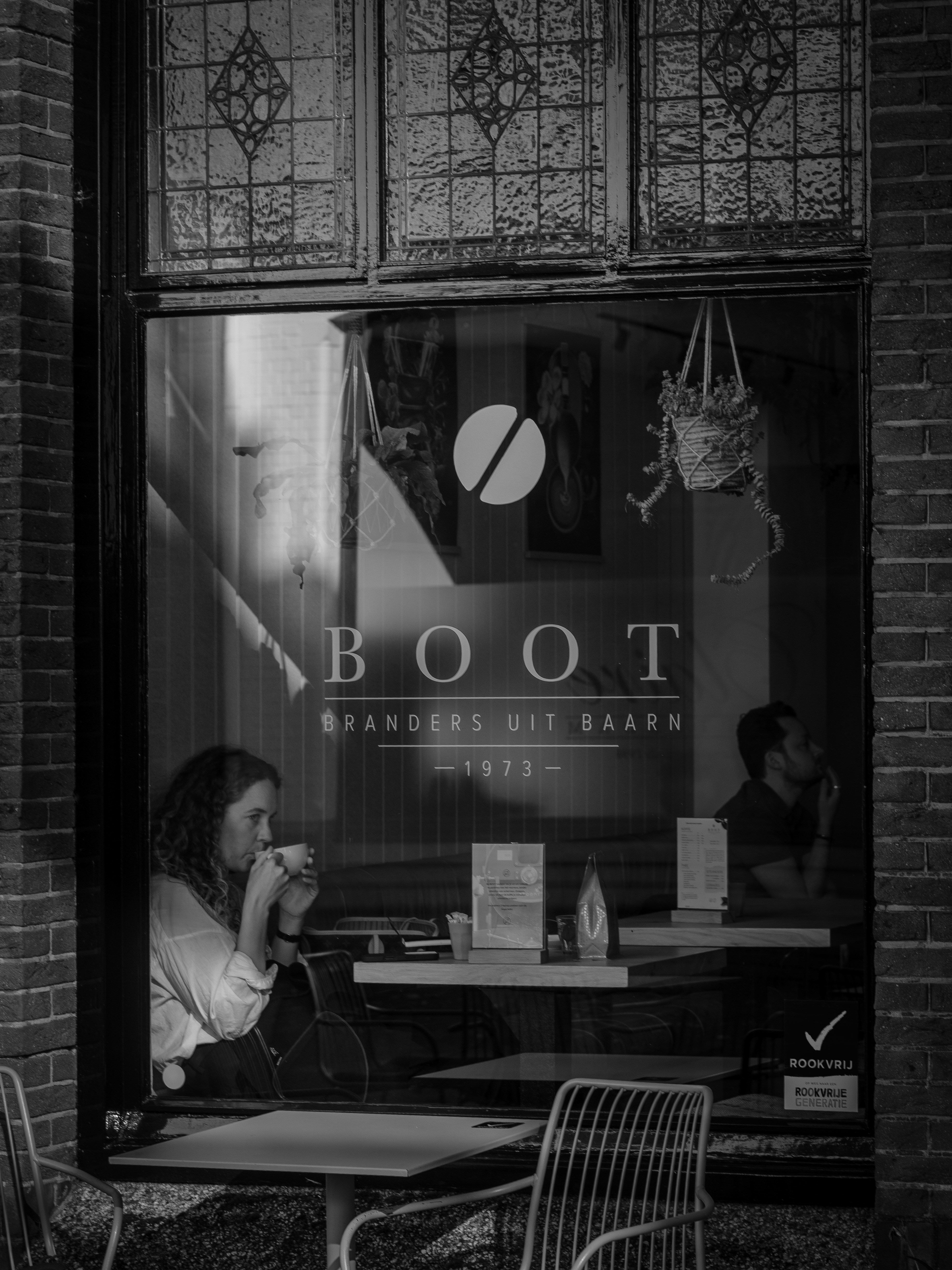 Woman drinking coffee inside a cafe window
