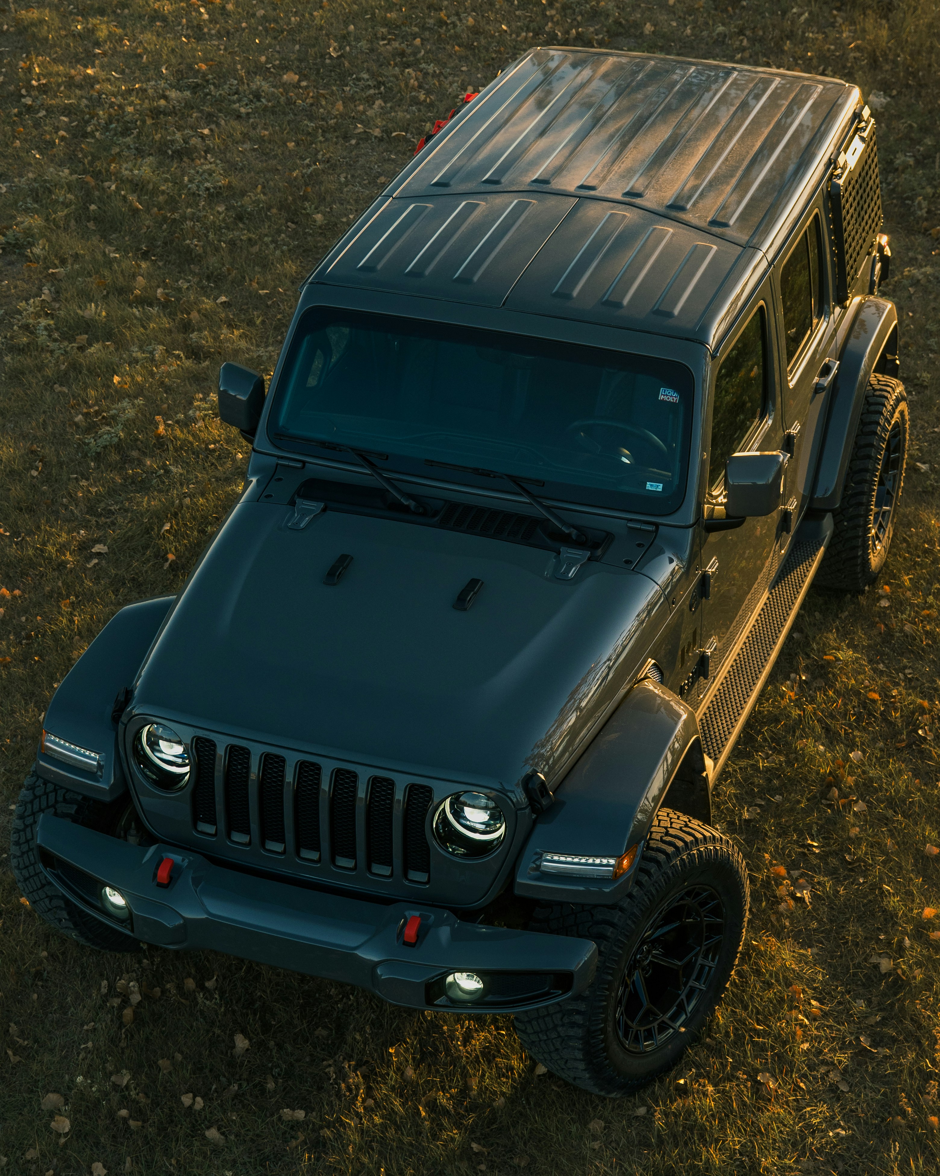 A dark grey jeep wrangler parked on grassy terrain.
