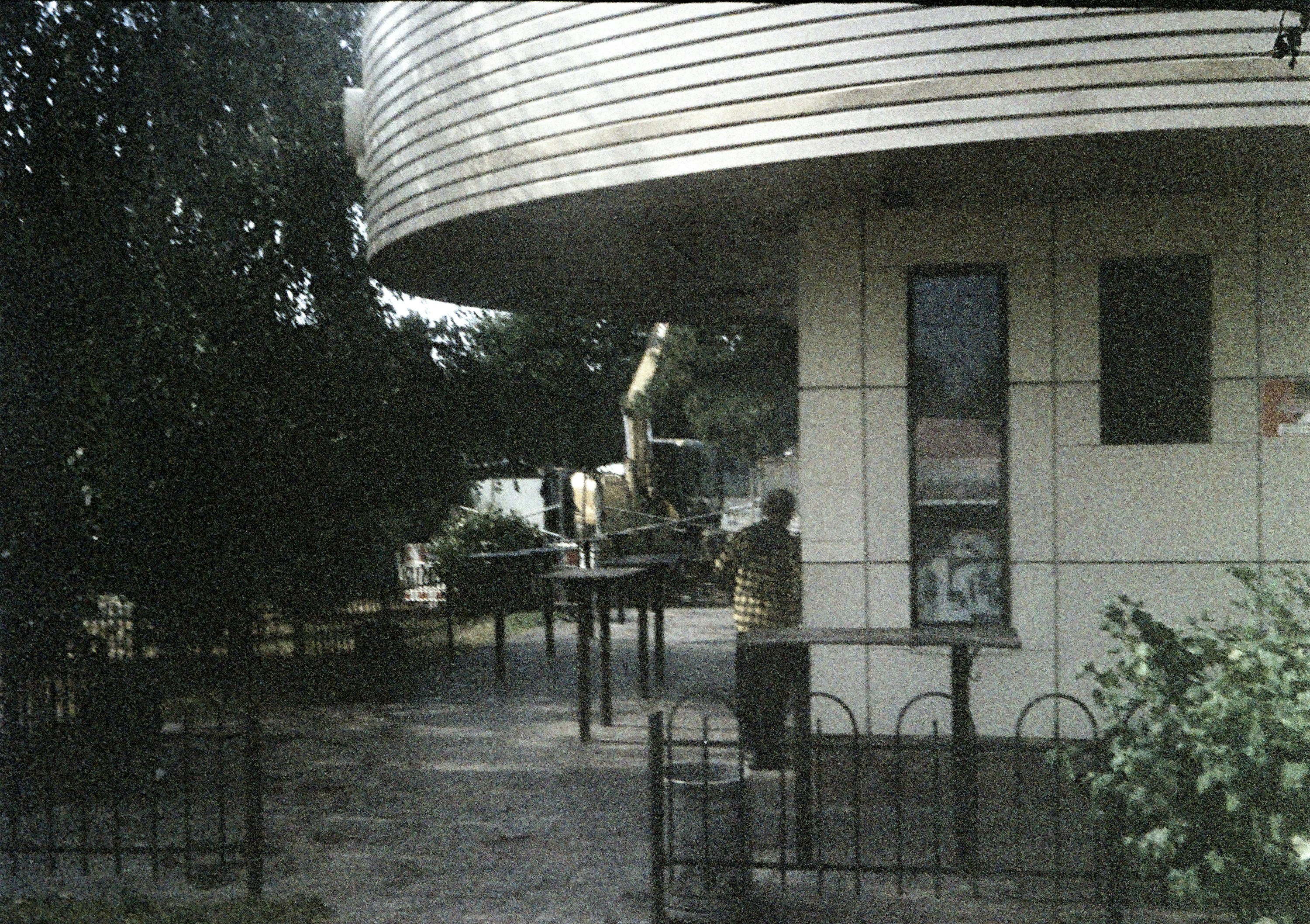 A person standing at a ticket booth with trees behind.