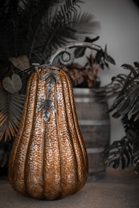 A decorative metallic pumpkin with ornate stem and leaves.