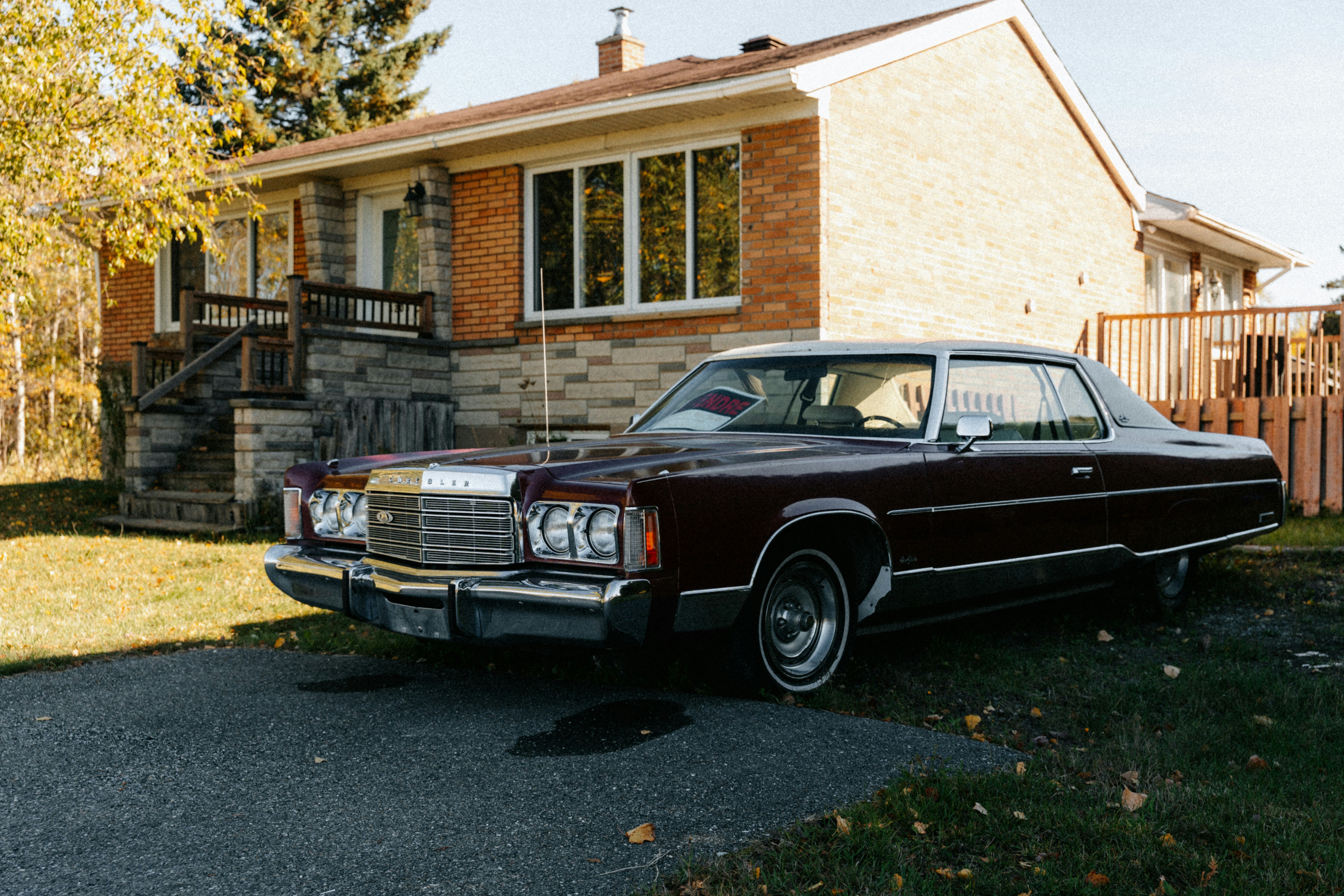 Maroon vintage car parked in front of brick house