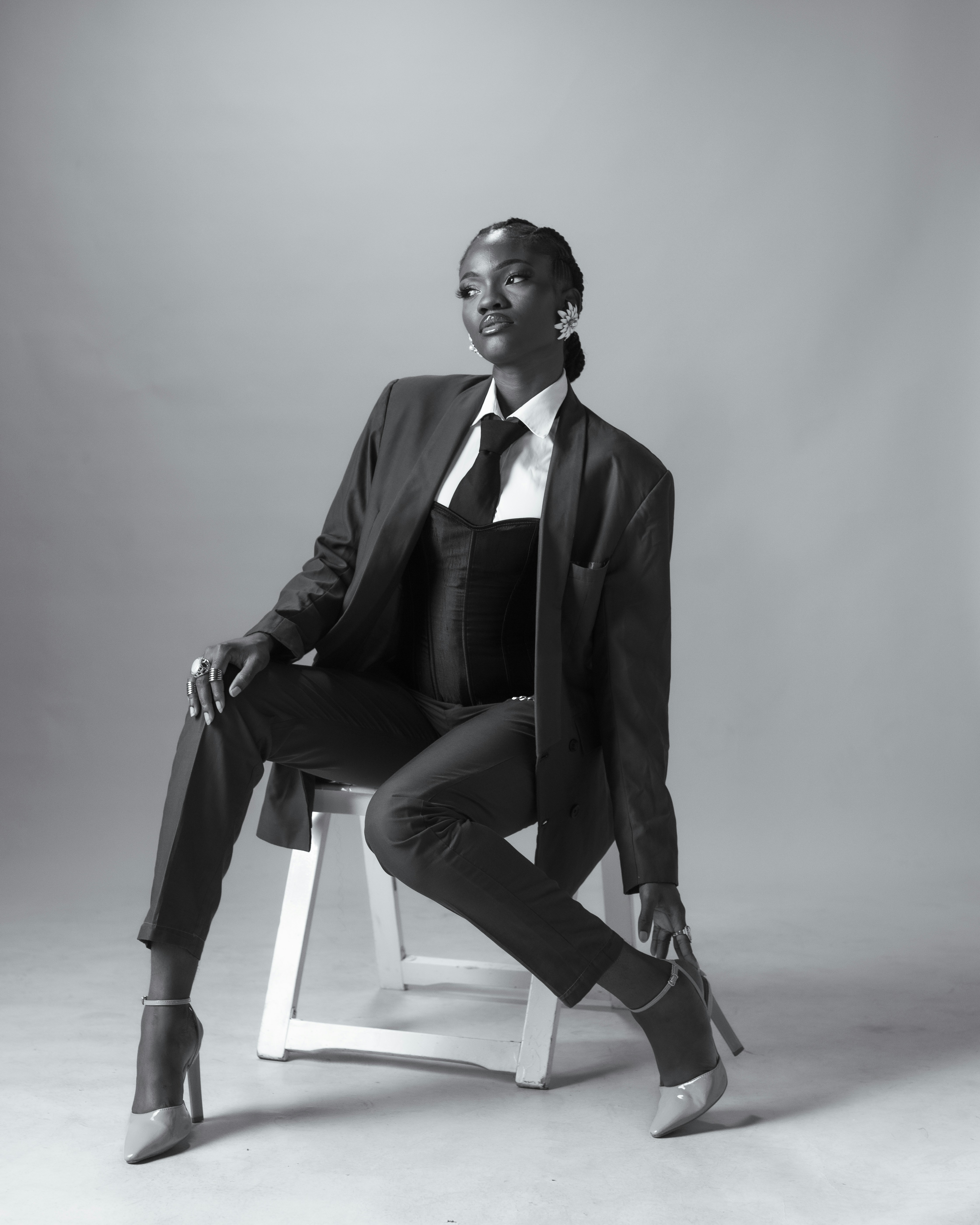 A woman in a suit sits on a chair.