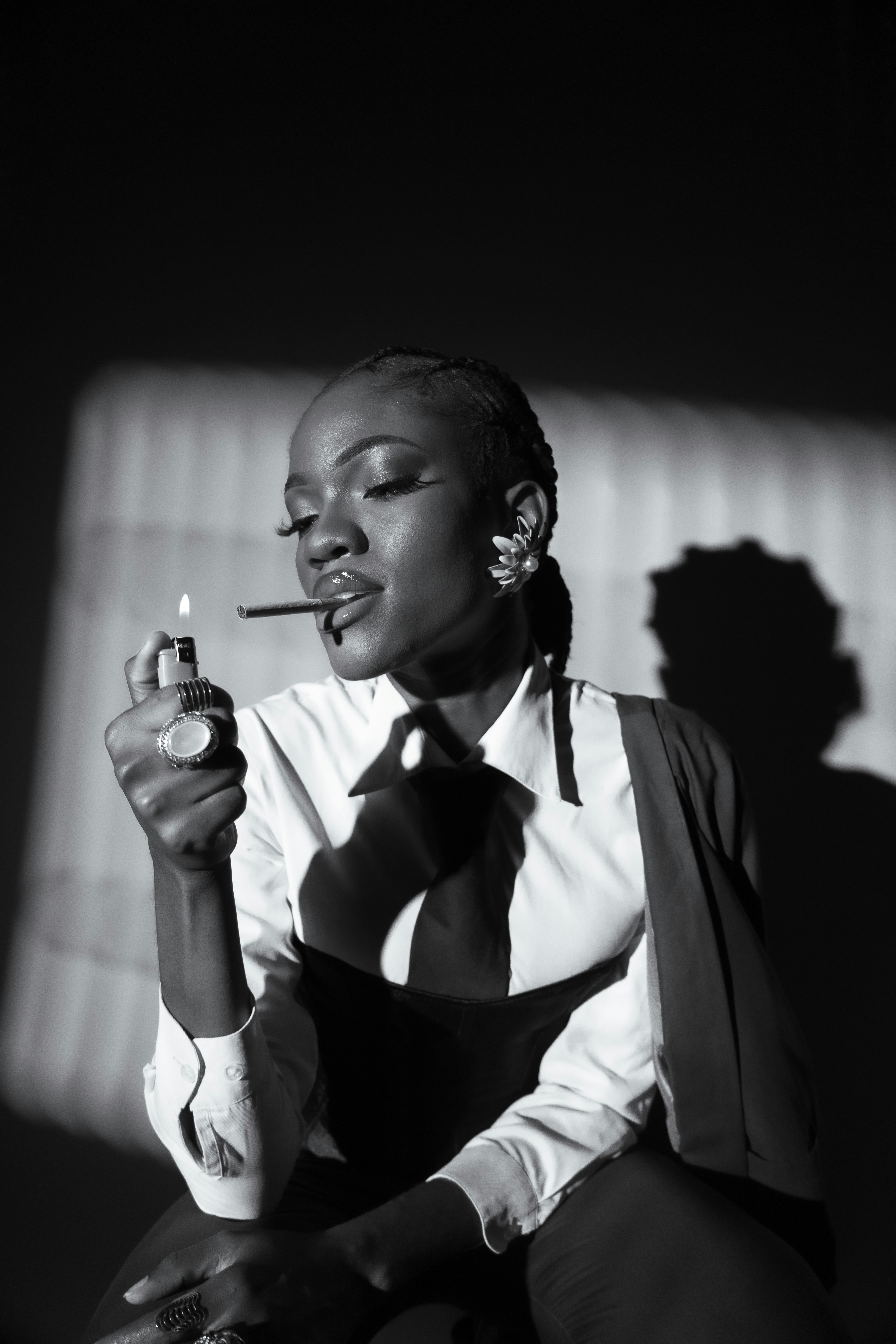 Woman lights cigarette with lighter in dramatic lighting