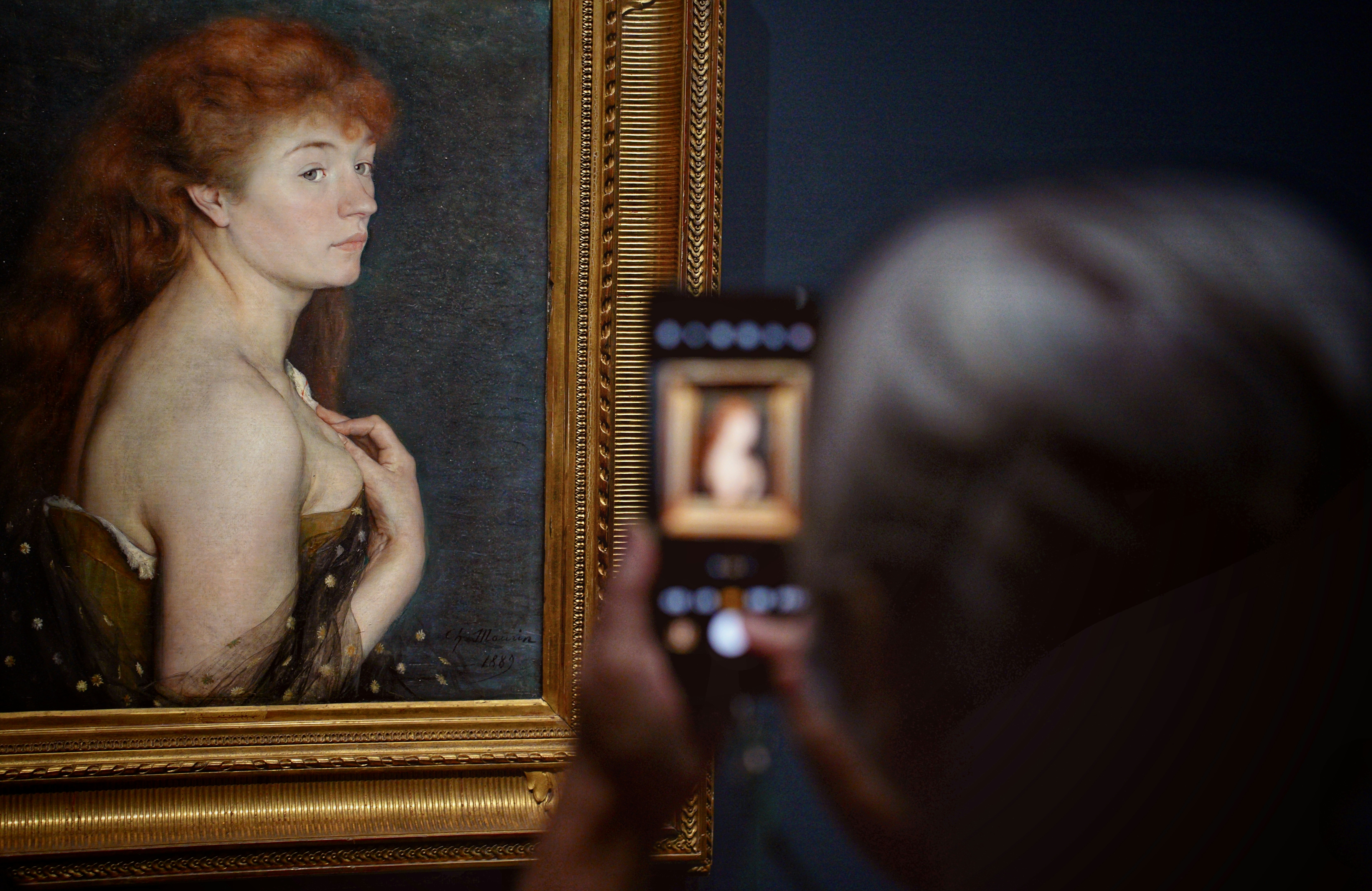 Person photographs a painting of a woman