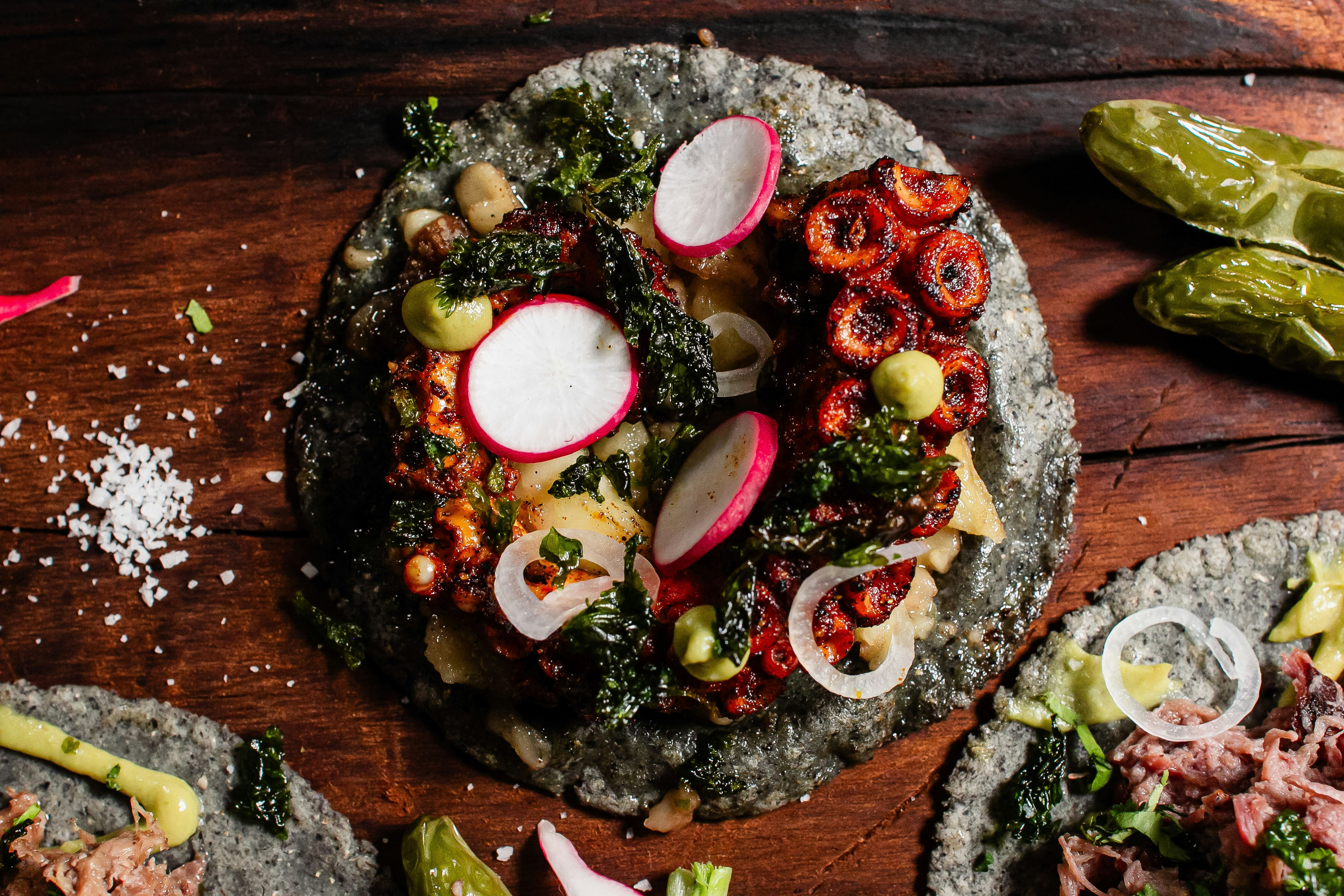 Tacos mit Oktopus, Rettich und Gemüse auf blauen Maistortillas