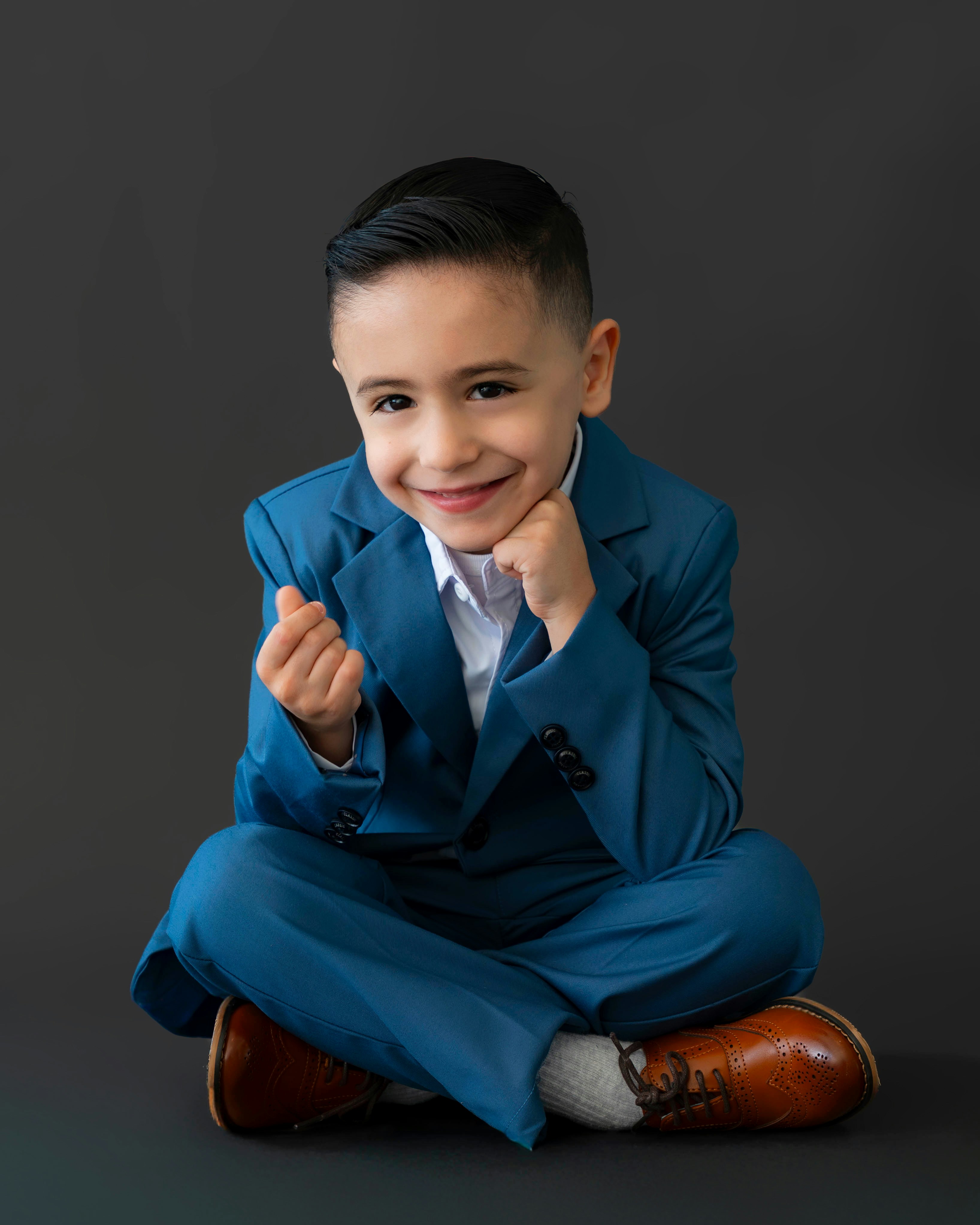 Un niño con un traje azul sonríe.