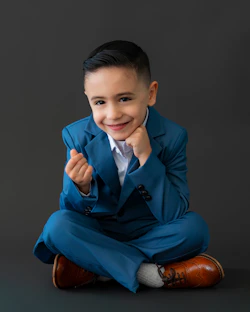 A young boy in a blue suit smiles