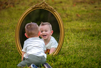 A baby smiles at their reflection in a mirror.