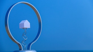 A miniature house inside a lightbulb on blue background