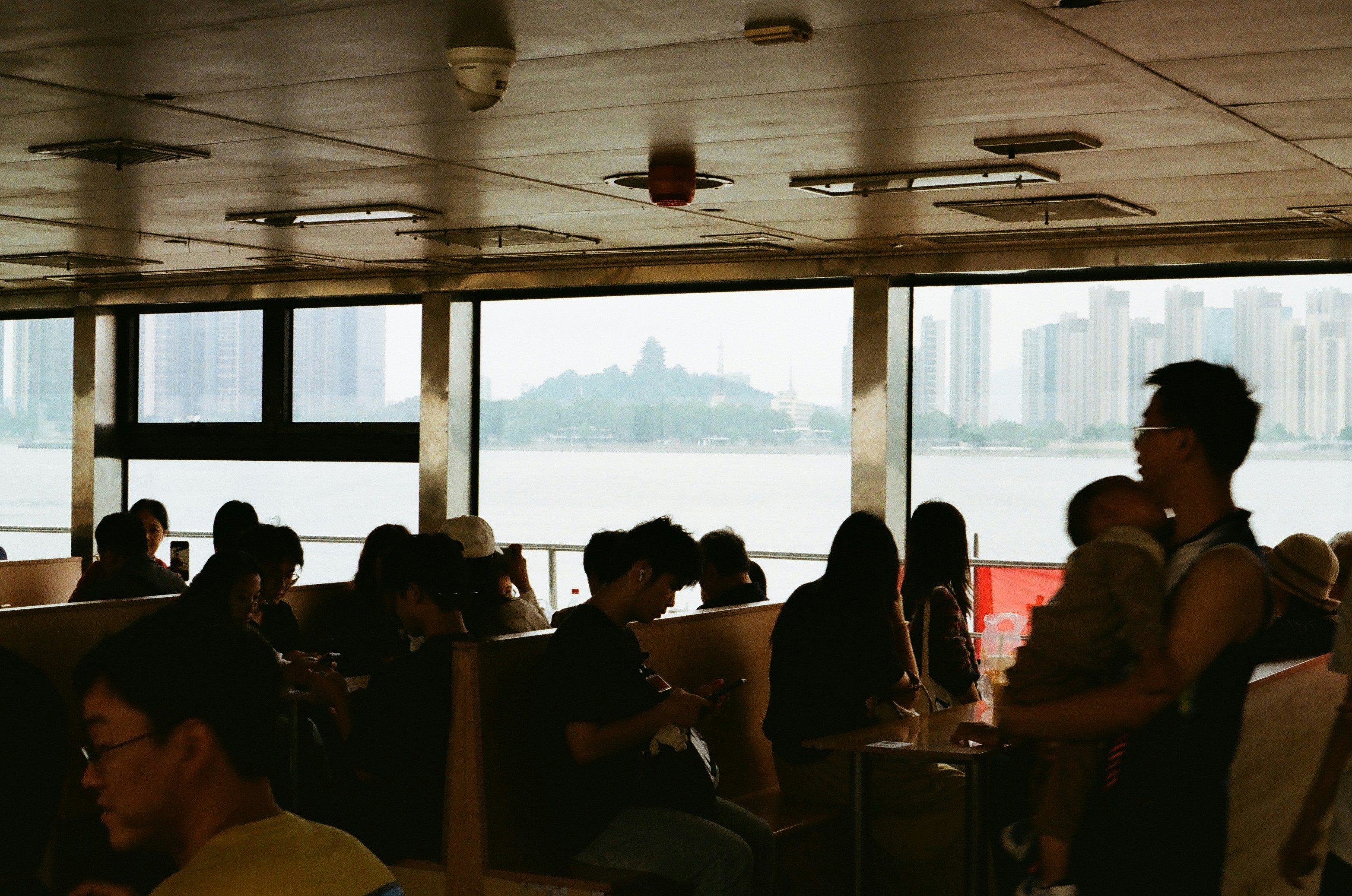 People on a ferry with city skyline view.