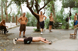 Men exercising outdoors with an ab roller wheel.