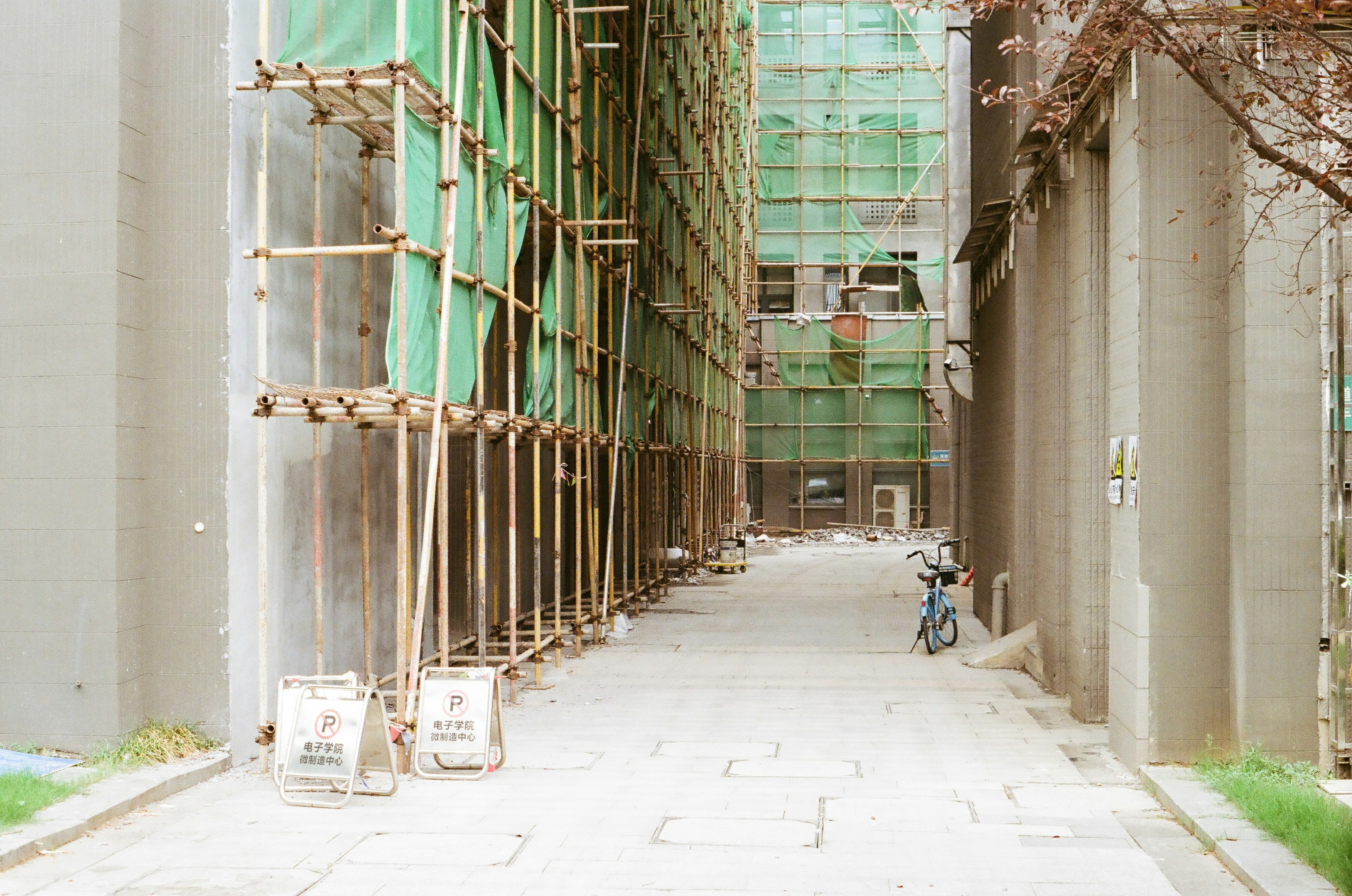 Buildings under construction with scaffolding and green netting.