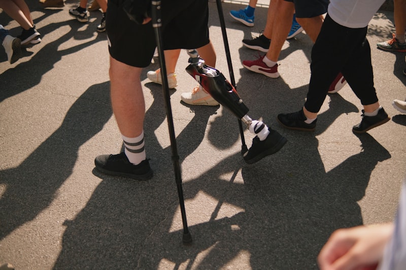 Person with a prosthetic leg walking outdoors with crutches