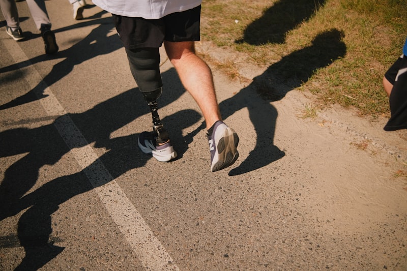 Runner with a prosthetic blade leg racing on an asphalt path