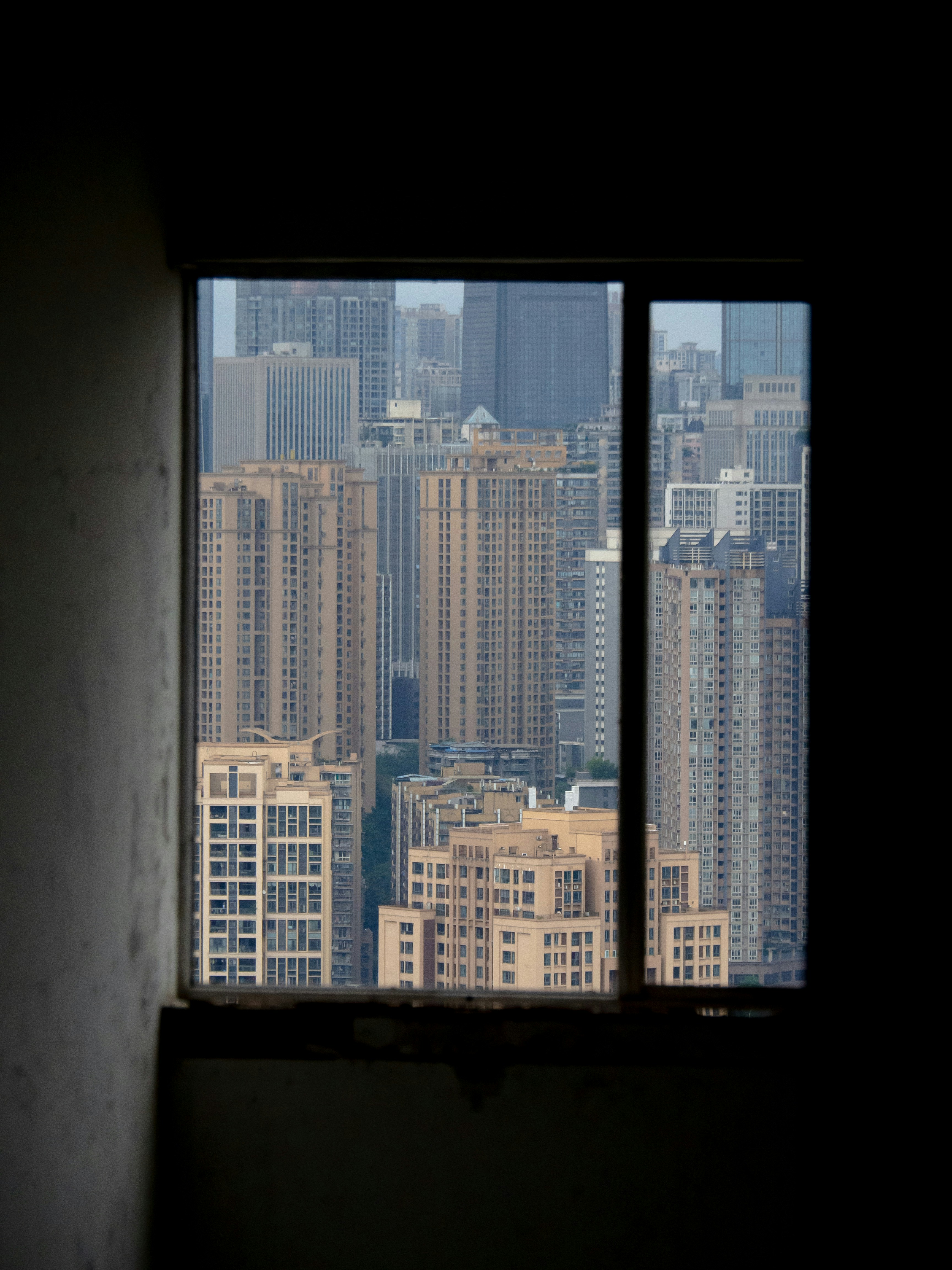 City skyline viewed through a dark window frame.
