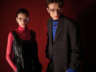 Two models posing in stylish eyeglasses against red background